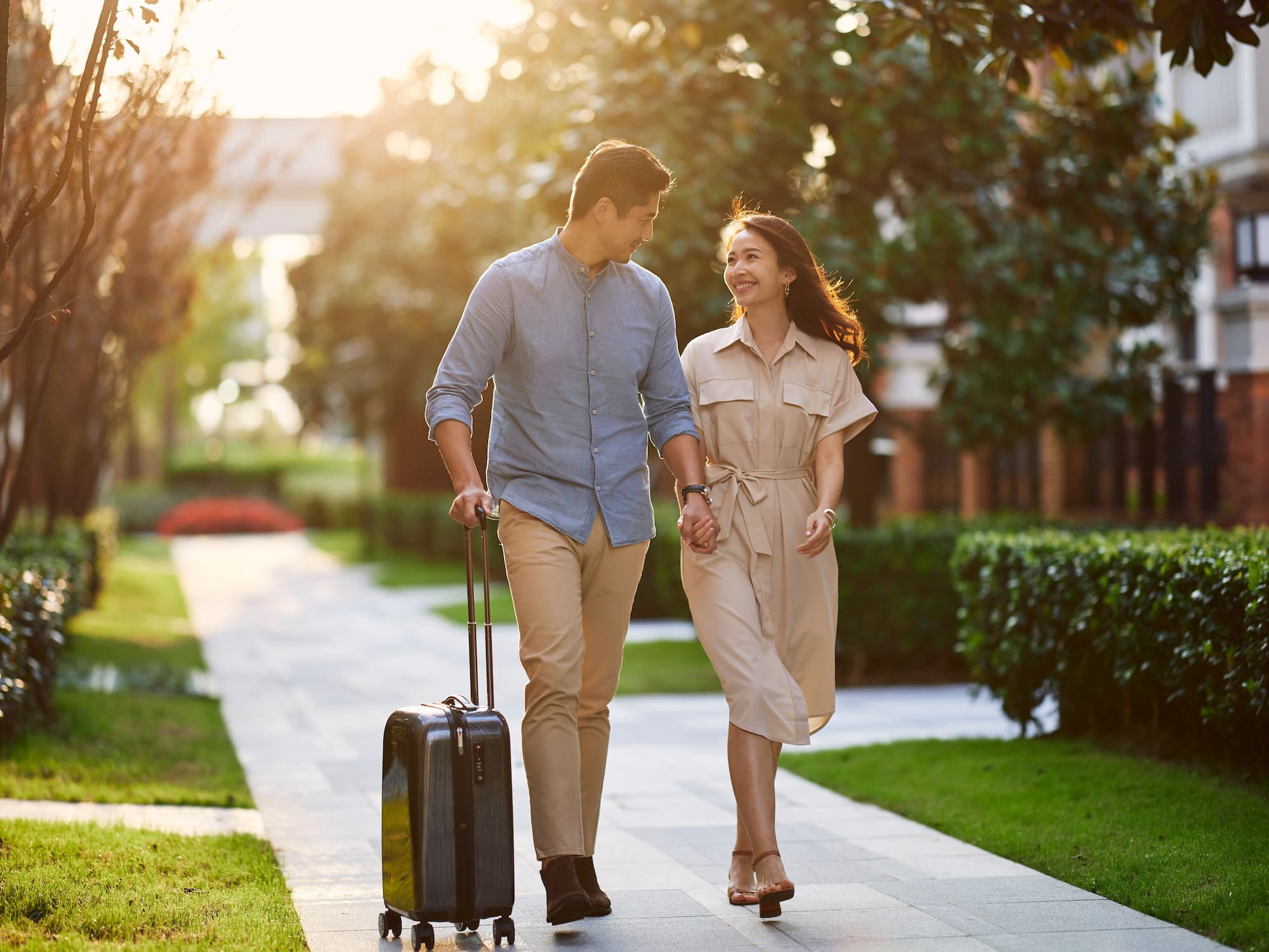 a man and woman holding hands and walking with luggage