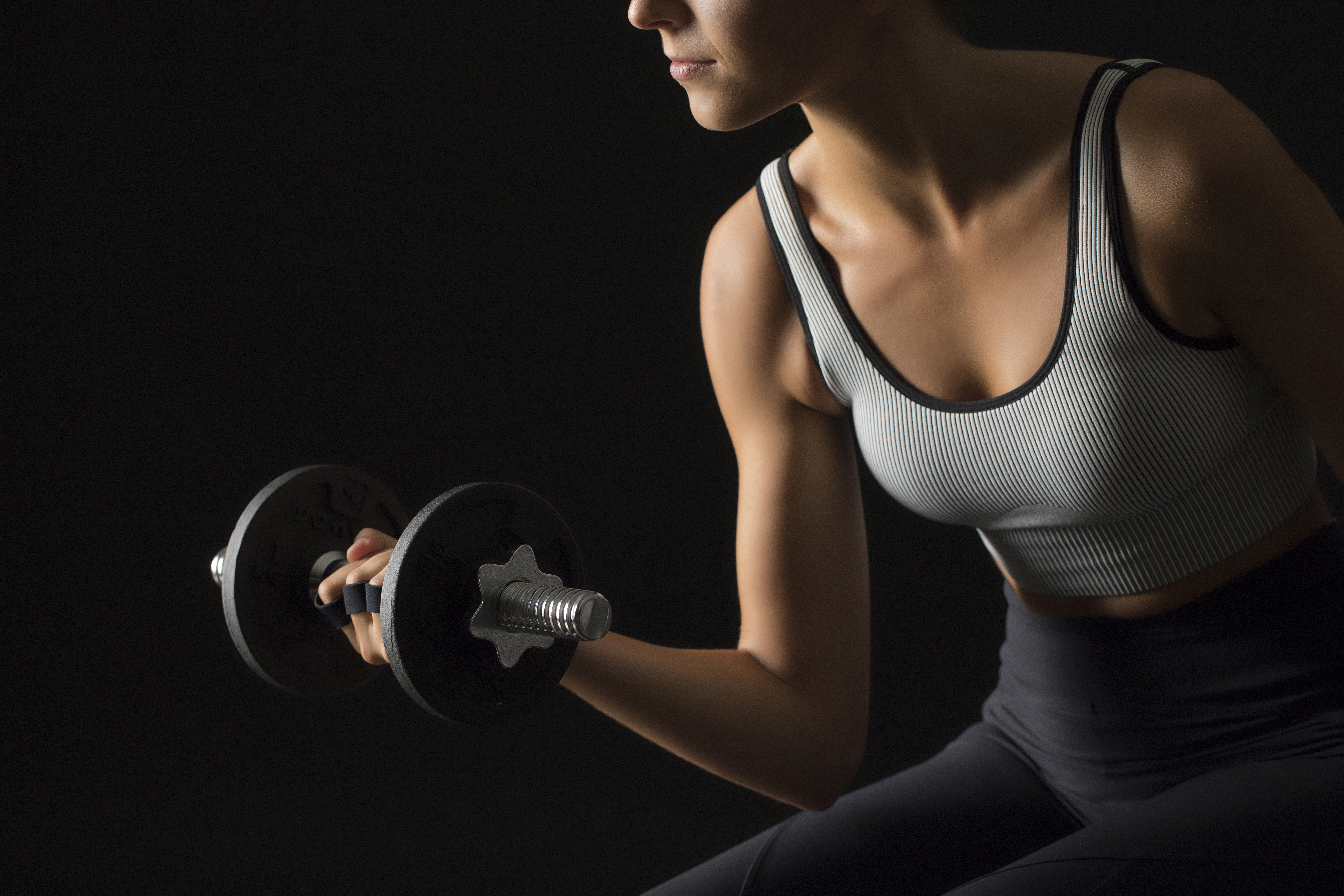 Woman training arm strength with dumbbell bicep curl.