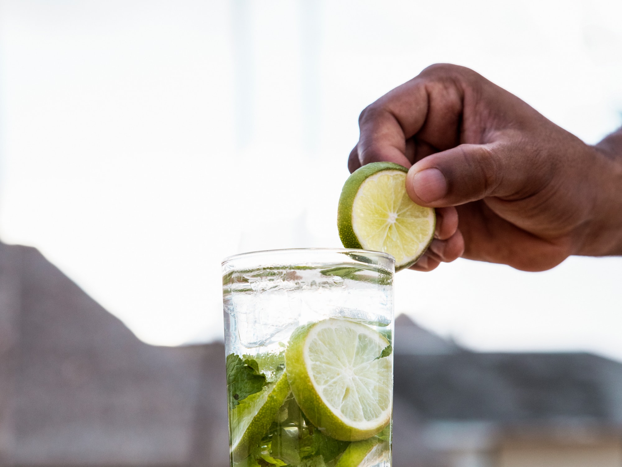 a person putting lime into a glass of water