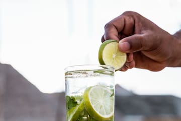 a person putting lime into a glass of water