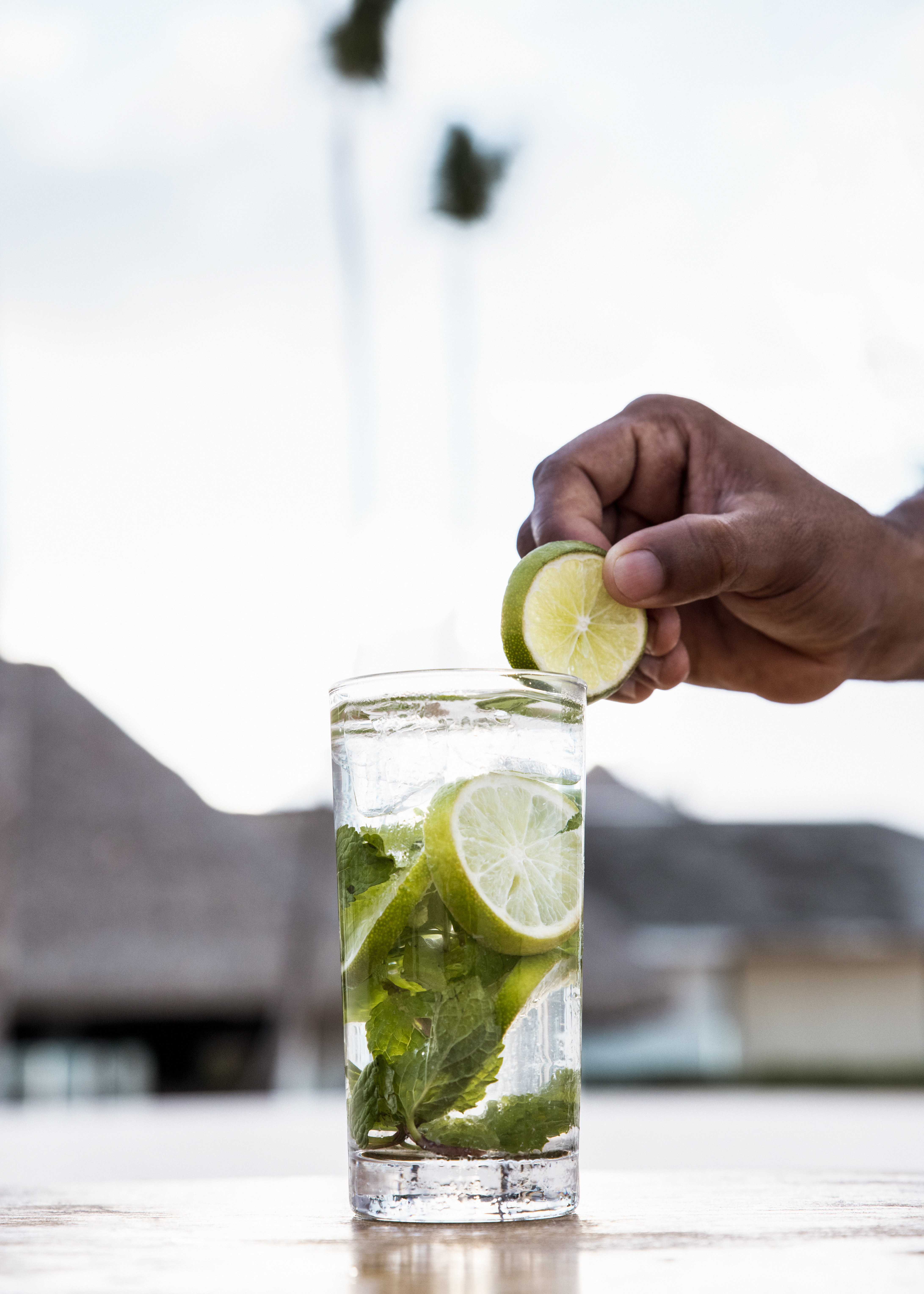a person putting lime into a glass of water