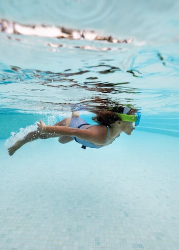 a woman swimming underwater with goggles