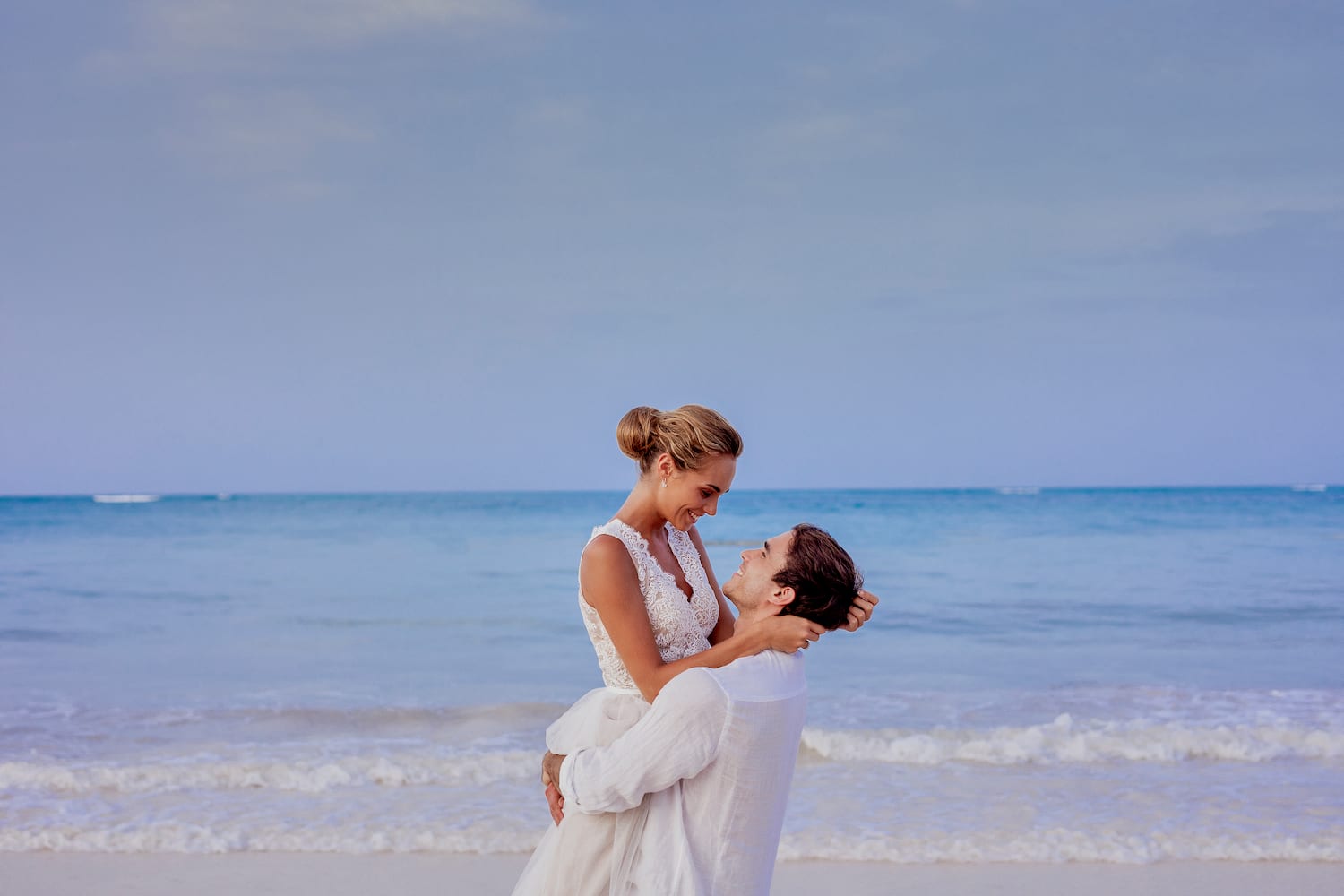 a man holding a woman on his back on a beach