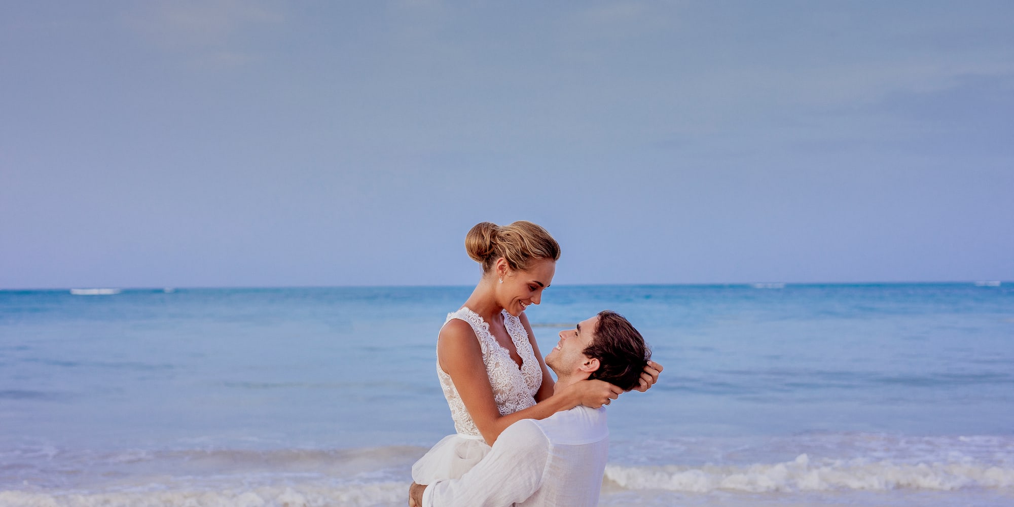a man holding a woman on his back on a beach