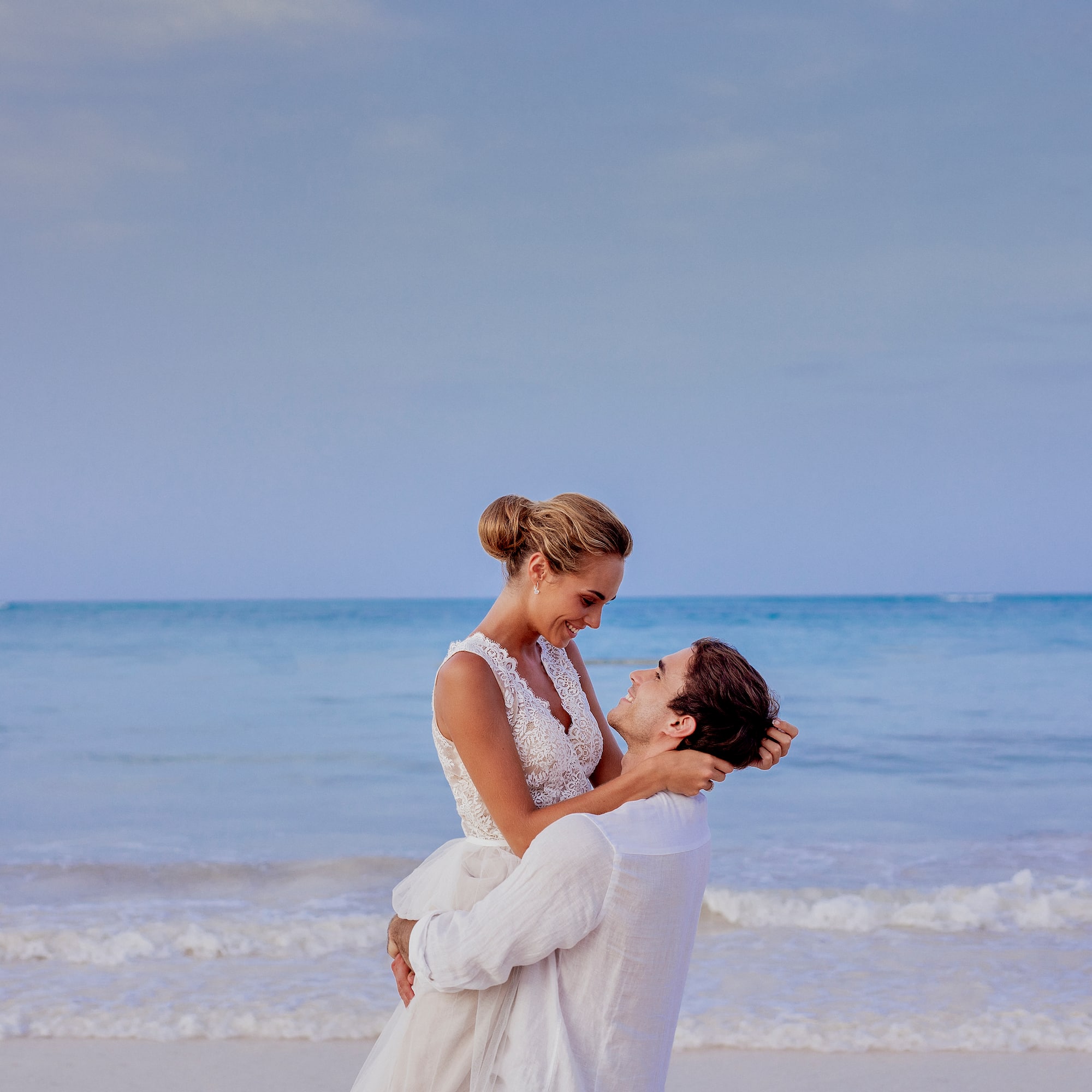 a man holding a woman on his back on a beach