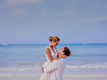 a man holding a woman on his back on a beach