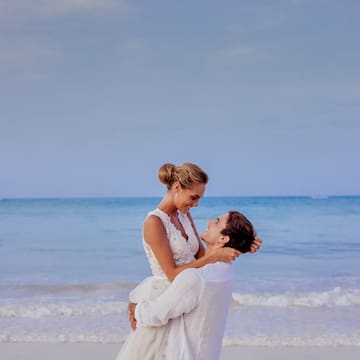 a man holding a woman on his back on a beach