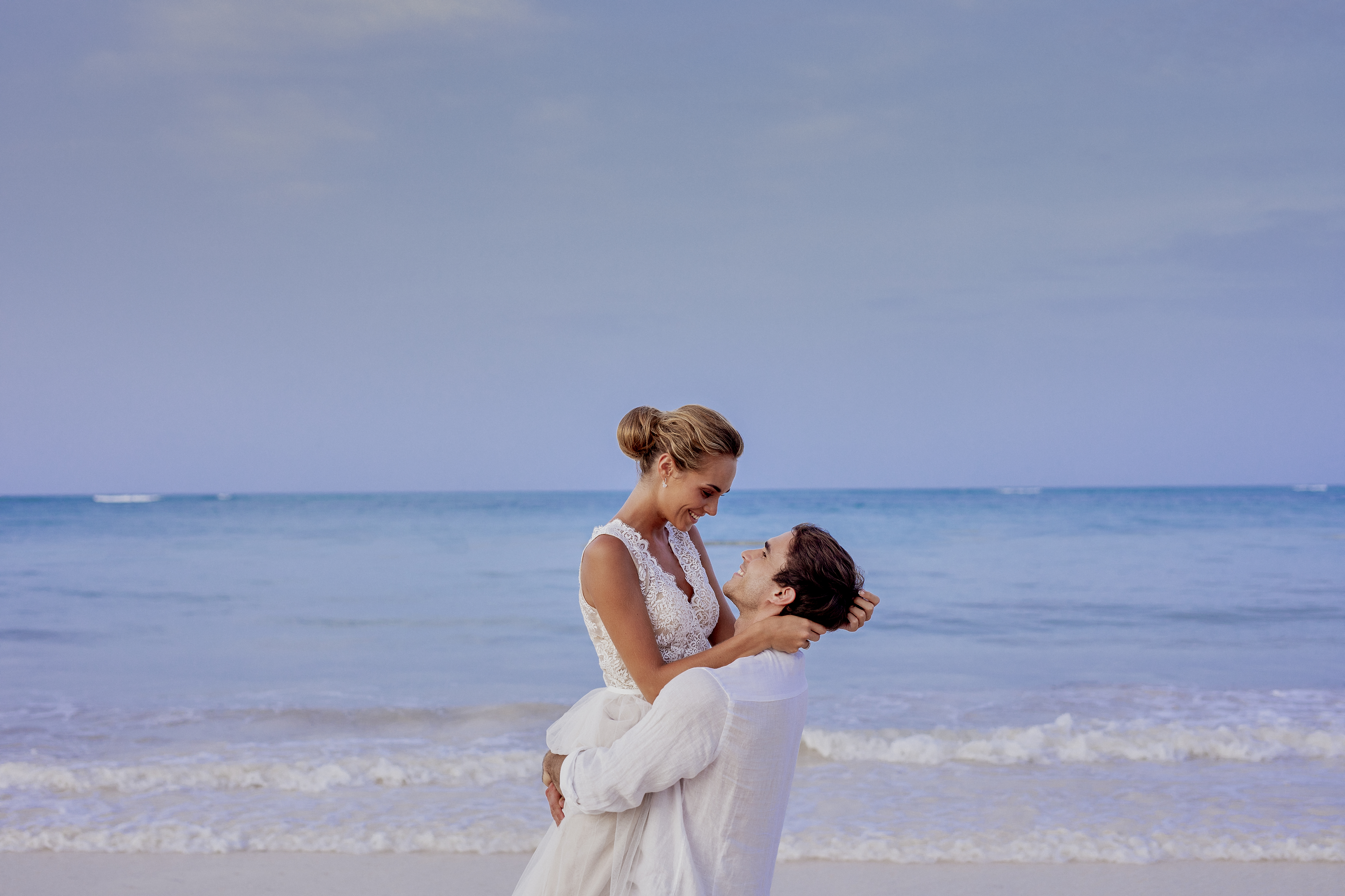 Smiling bride and groom embracing on a tropical beach wedding.