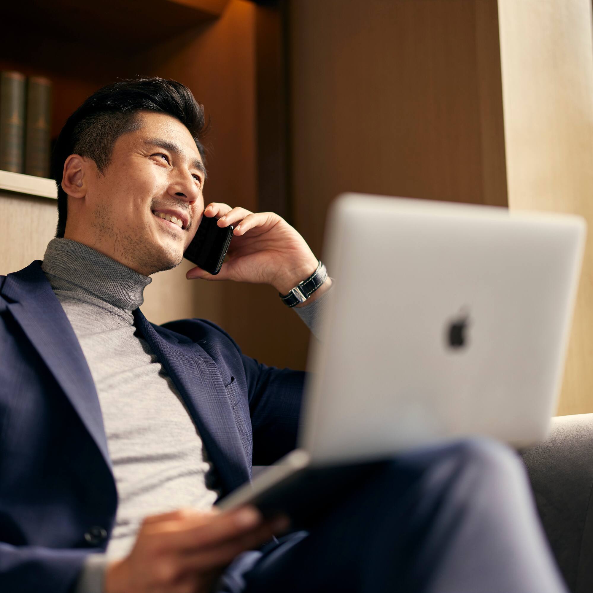a man sitting on a couch with a laptop and phone