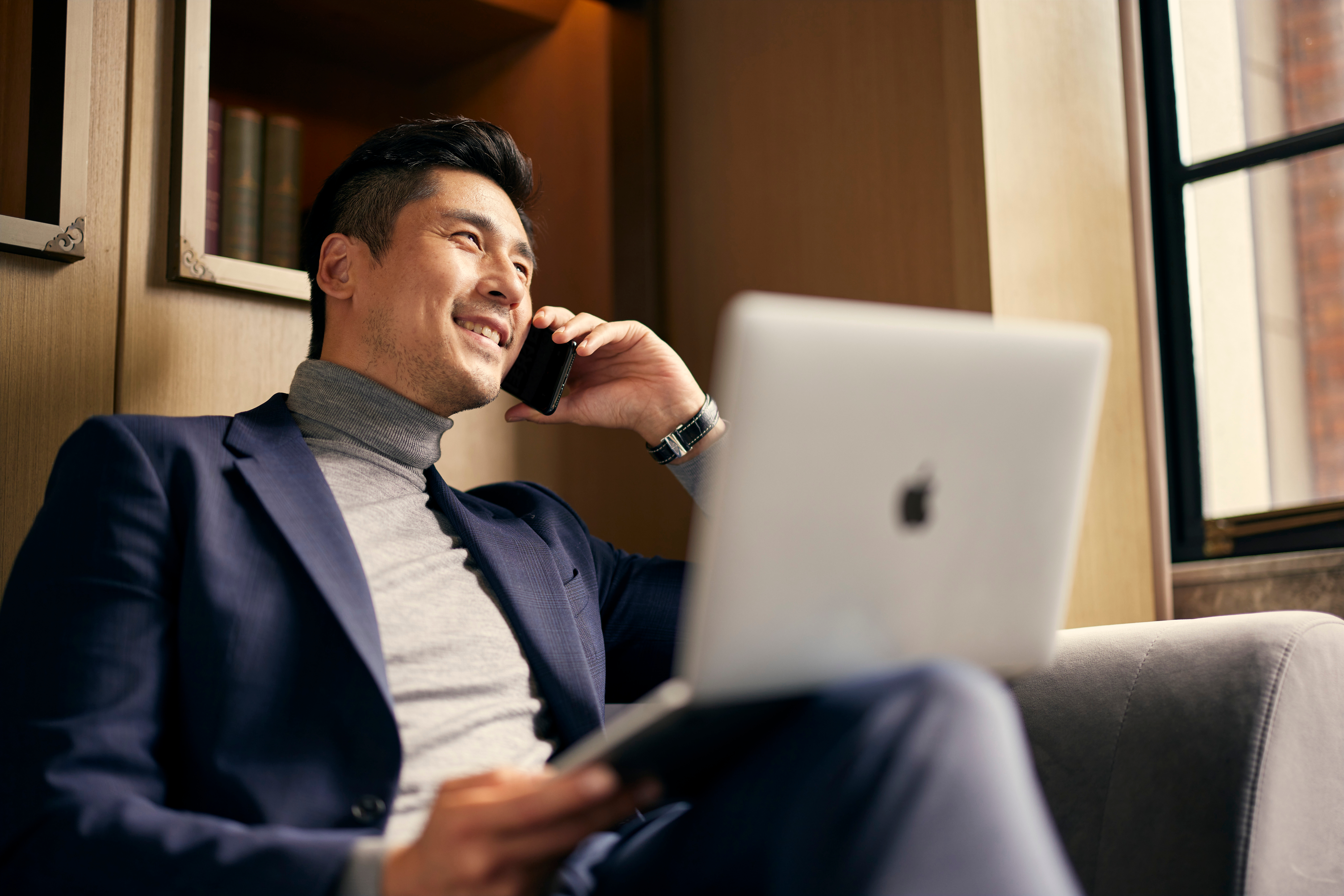 a man sitting on a couch with a laptop and phone