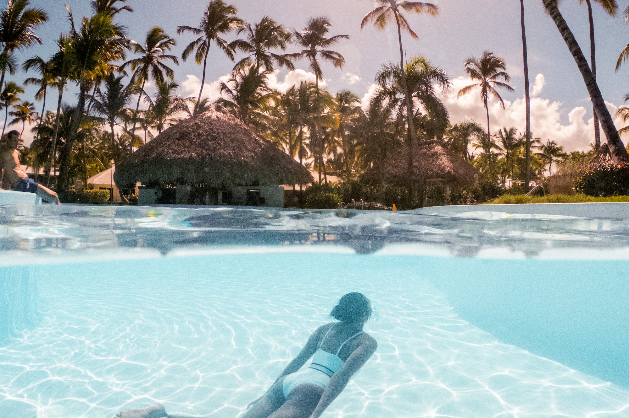 a woman in a white garment in a pool with palm trees