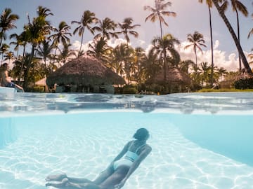 a woman in a white garment in a pool with palm trees