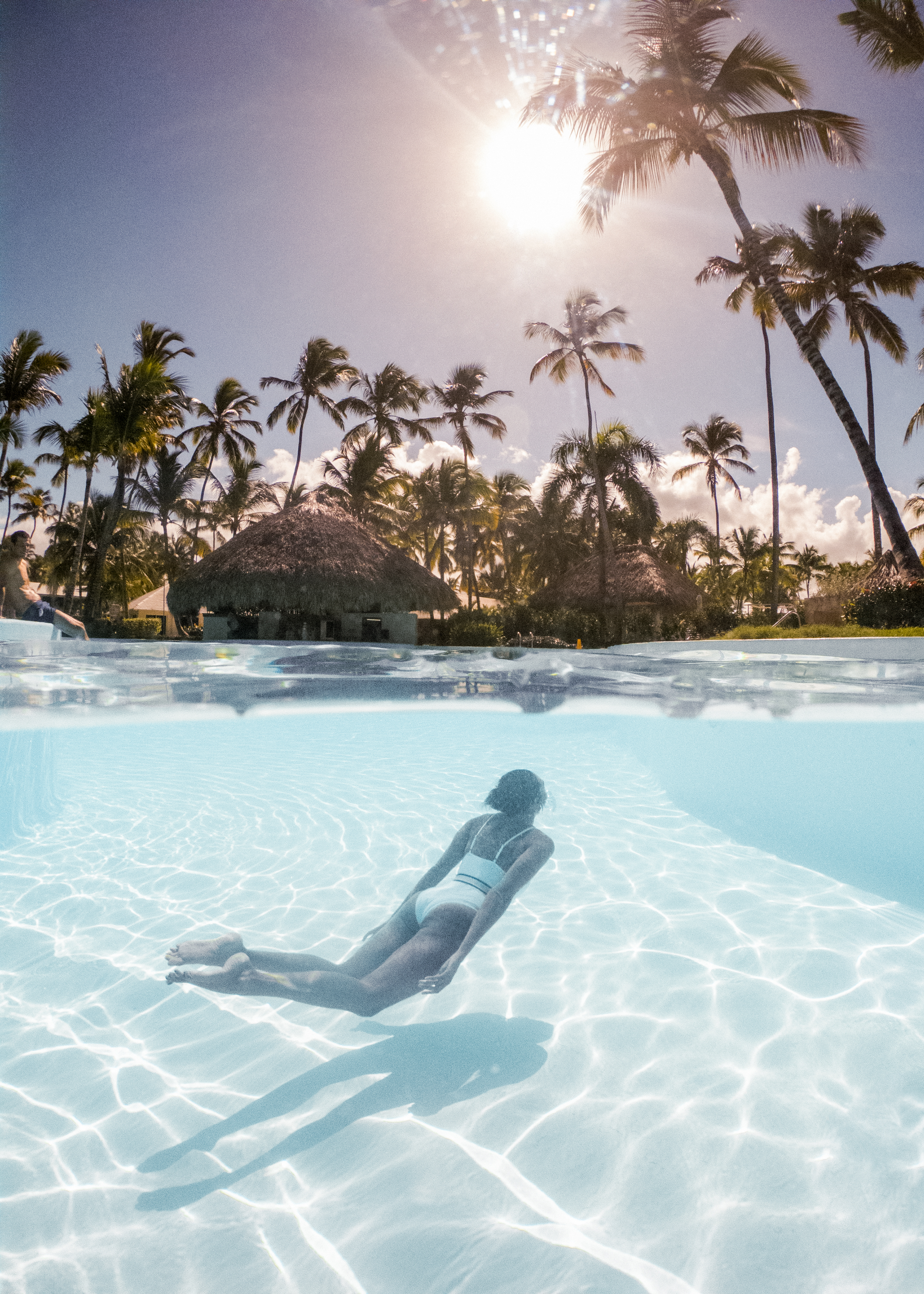 a woman in a white garment in a pool with palm trees