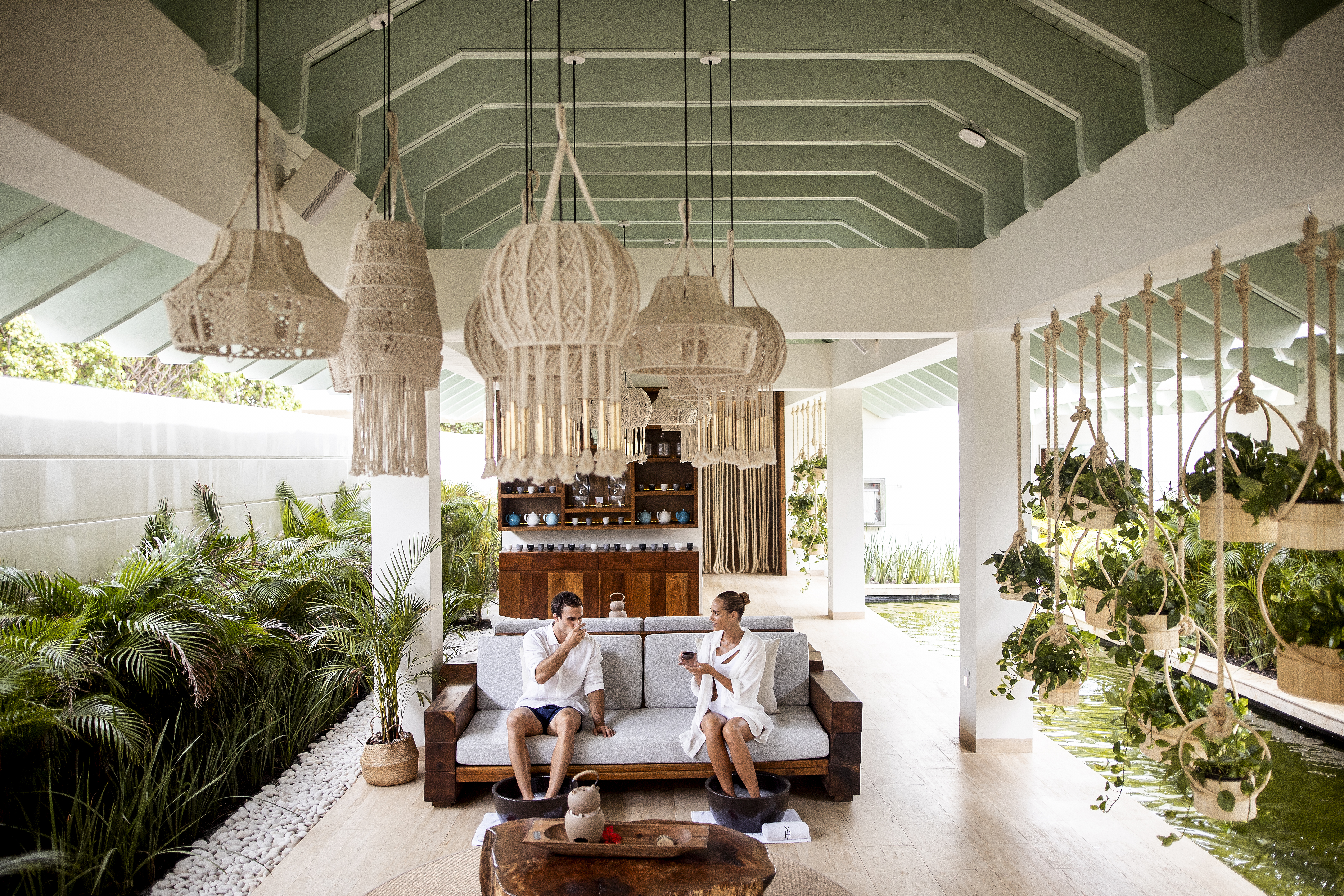 Couple relaxing with foot baths and drinks at a serene spa resort.