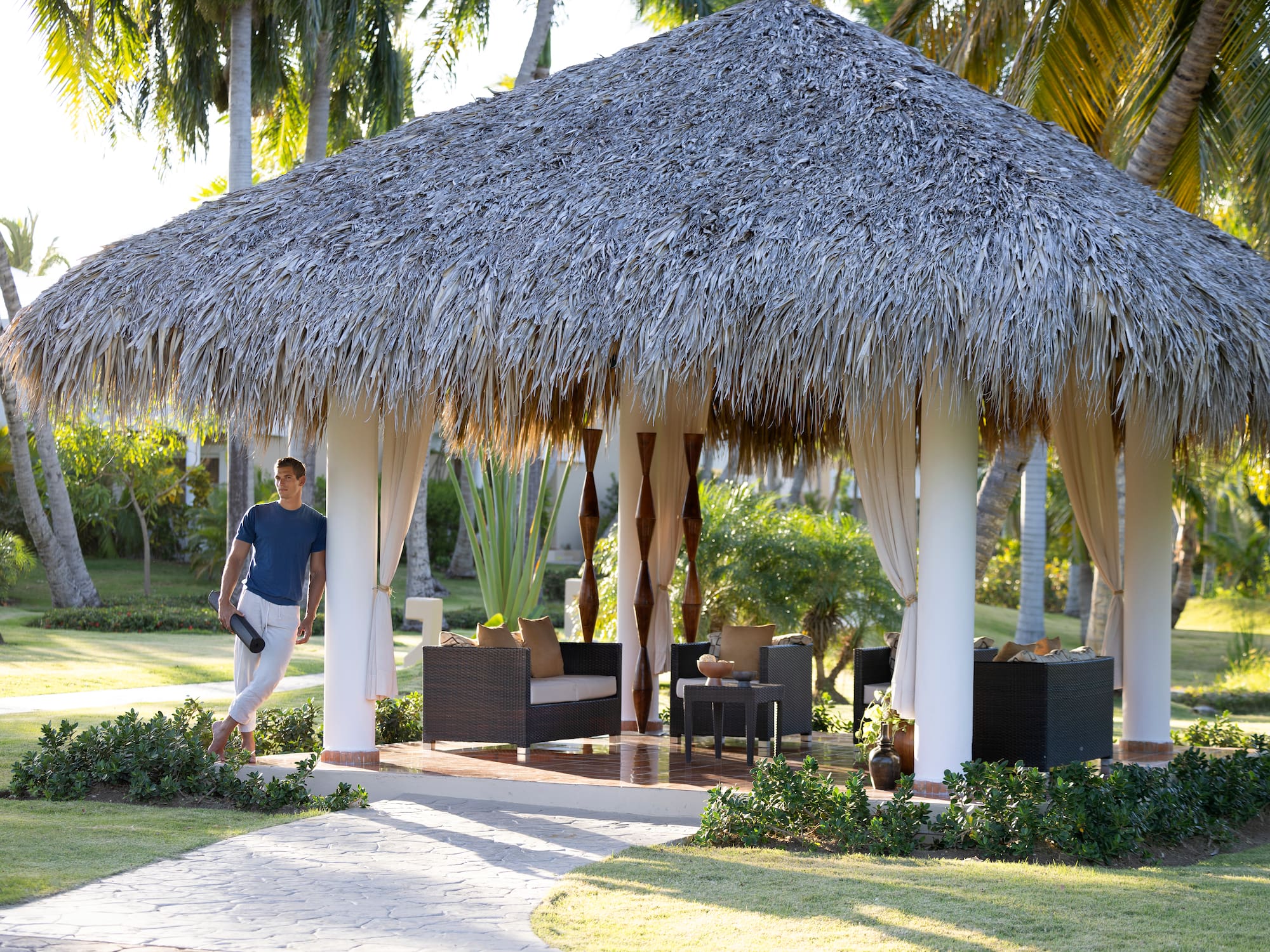 a man standing under a straw covered gazebo