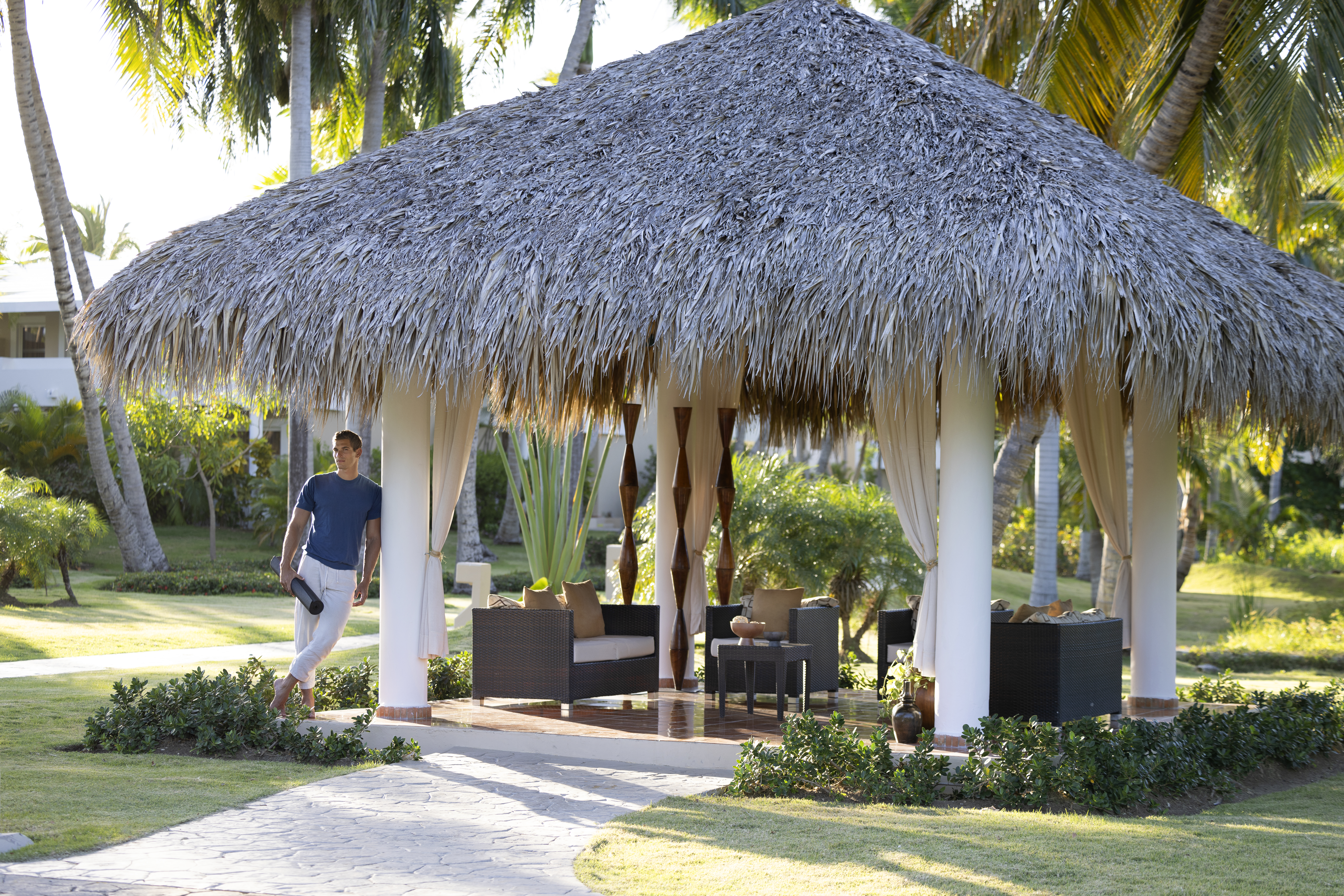 a man standing under a straw covered gazebo