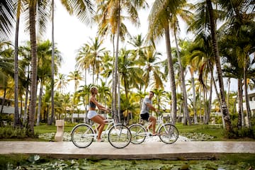 a man and woman riding bicycles under palm trees