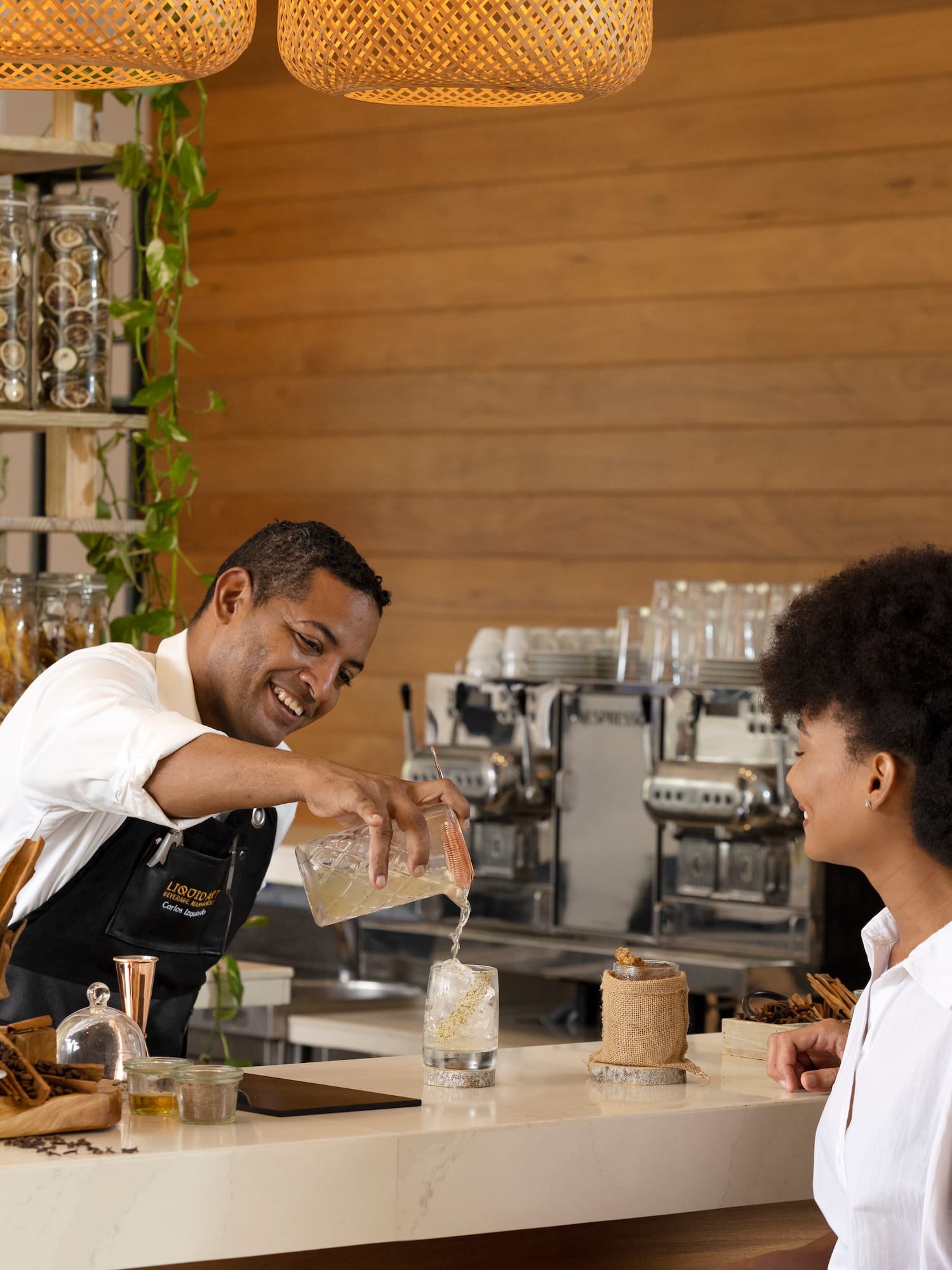 Bartender serves refreshing drink to couple at stylish cafe.