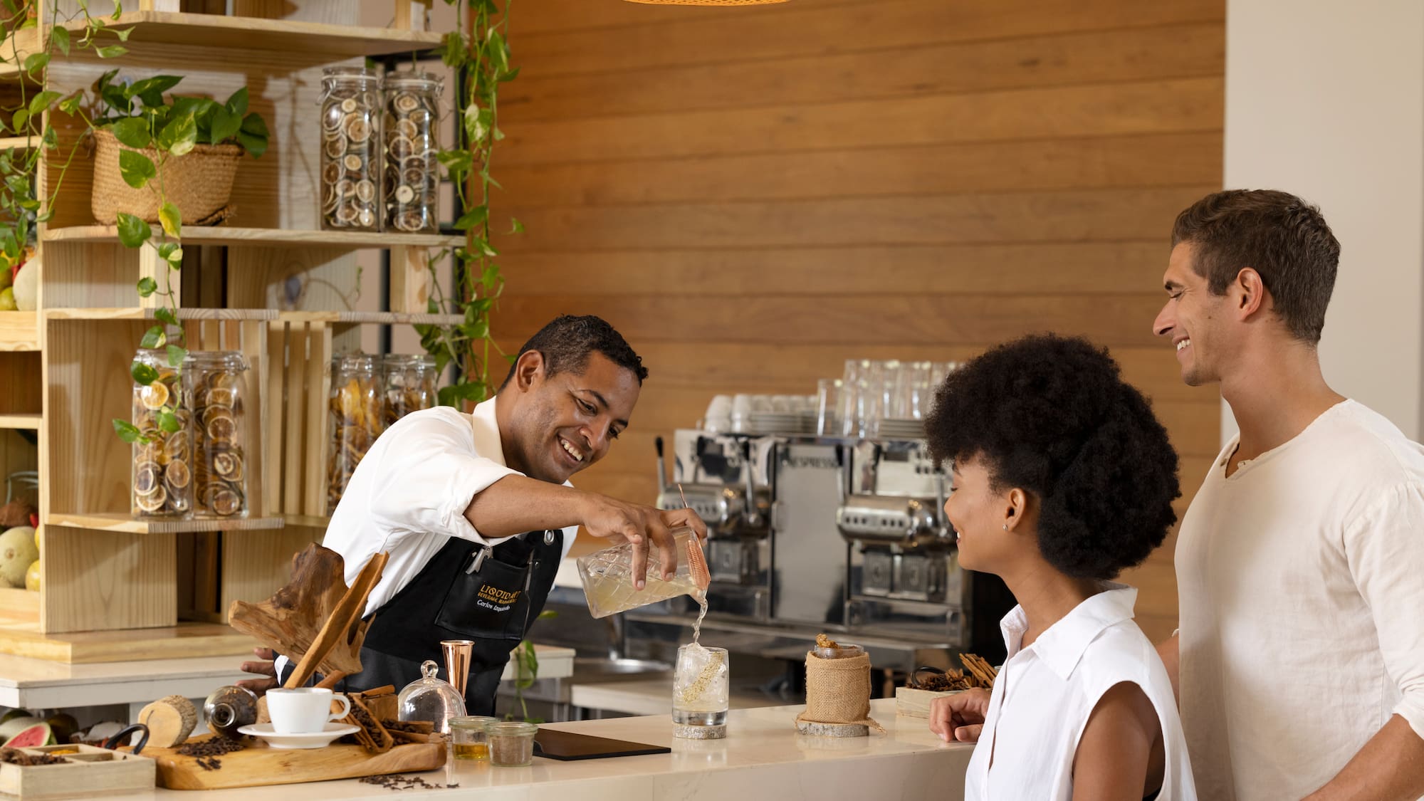 Smiling bartender pours beverage for guests at elegant hotel bar.