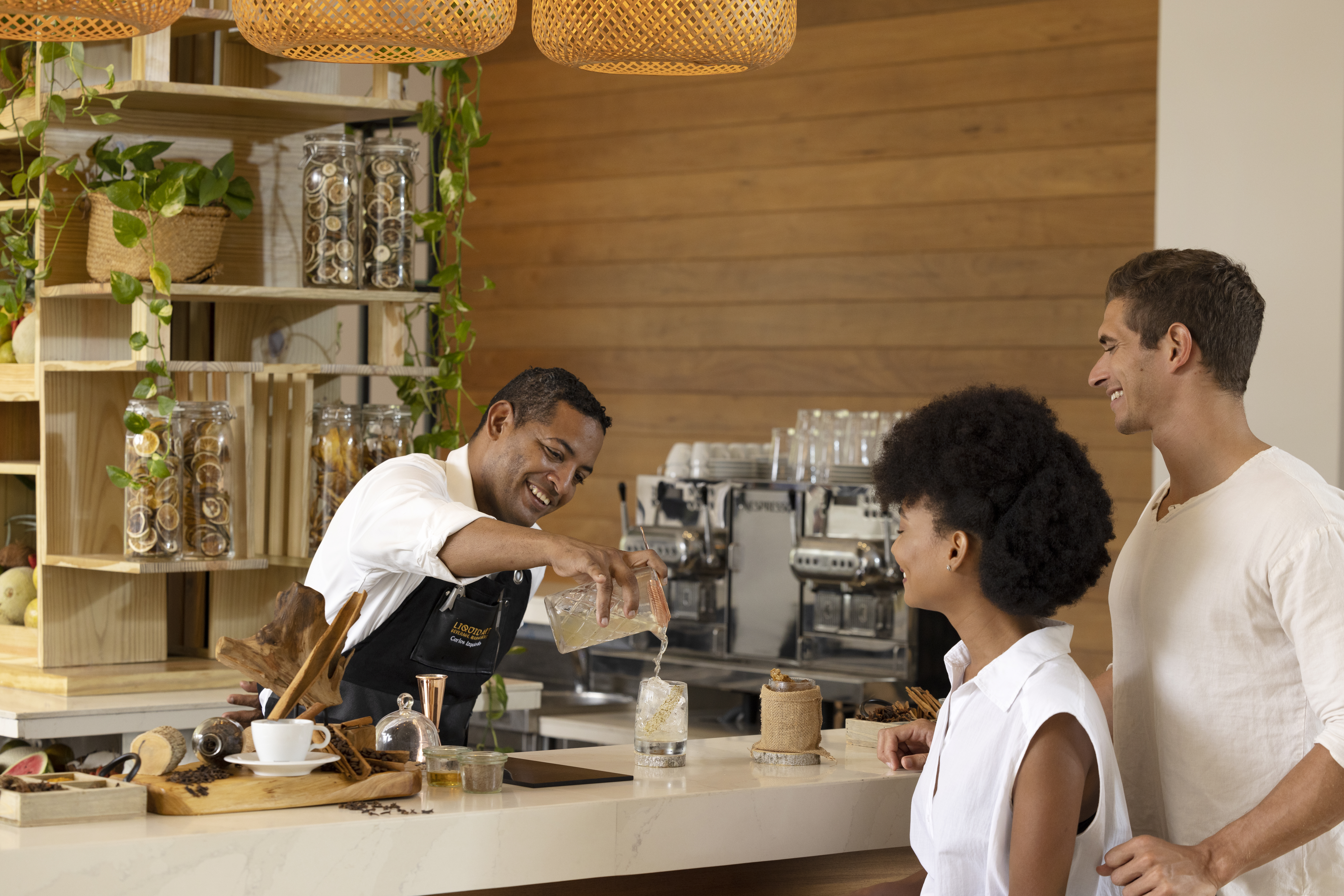 Bartender serves refreshing drink to couple at stylish cafe.