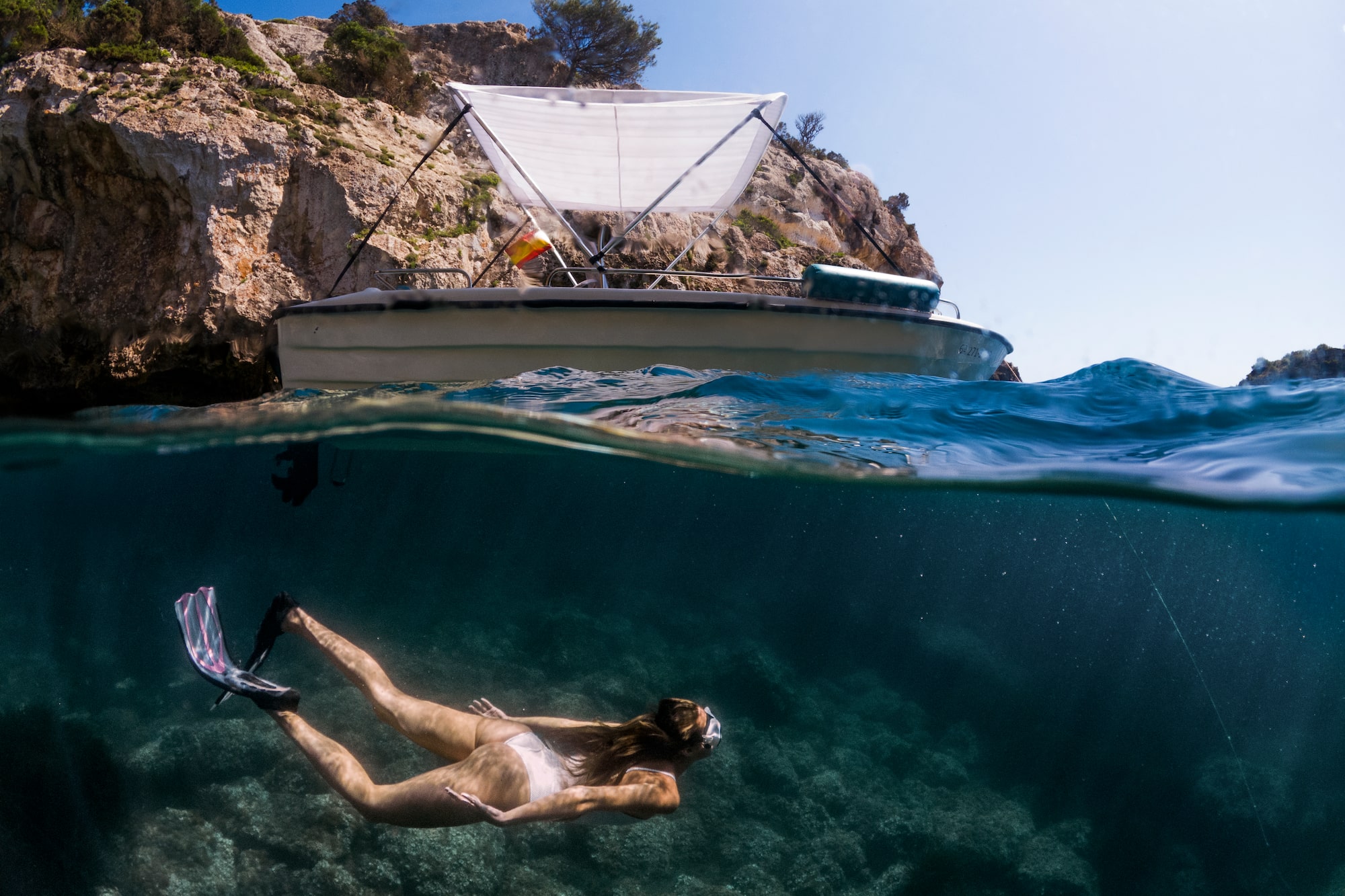 a woman in a garment underwater with a boat in the background