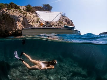 a woman in a garment underwater with a boat in the background