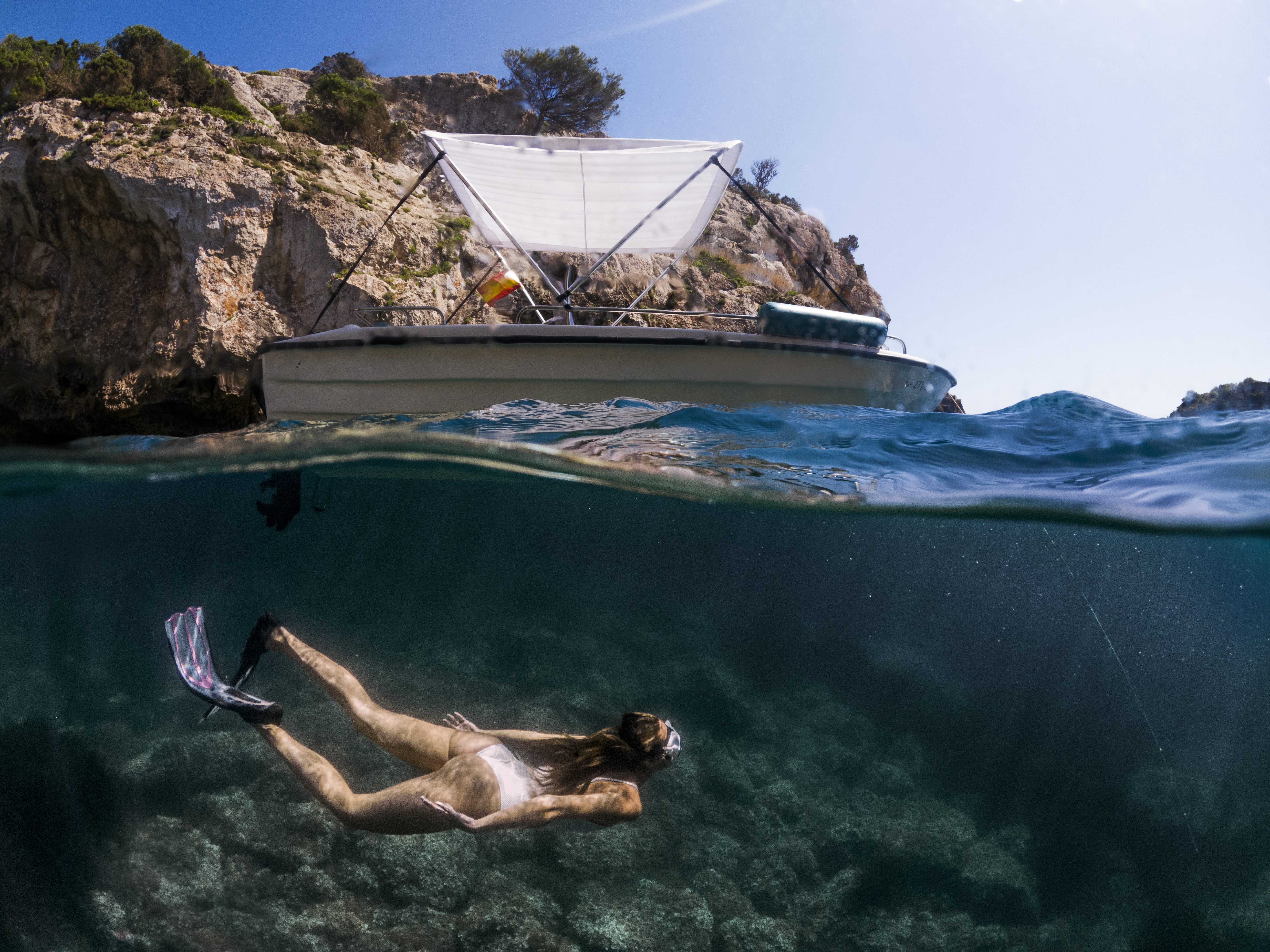 a woman in a garment underwater with a boat in the background