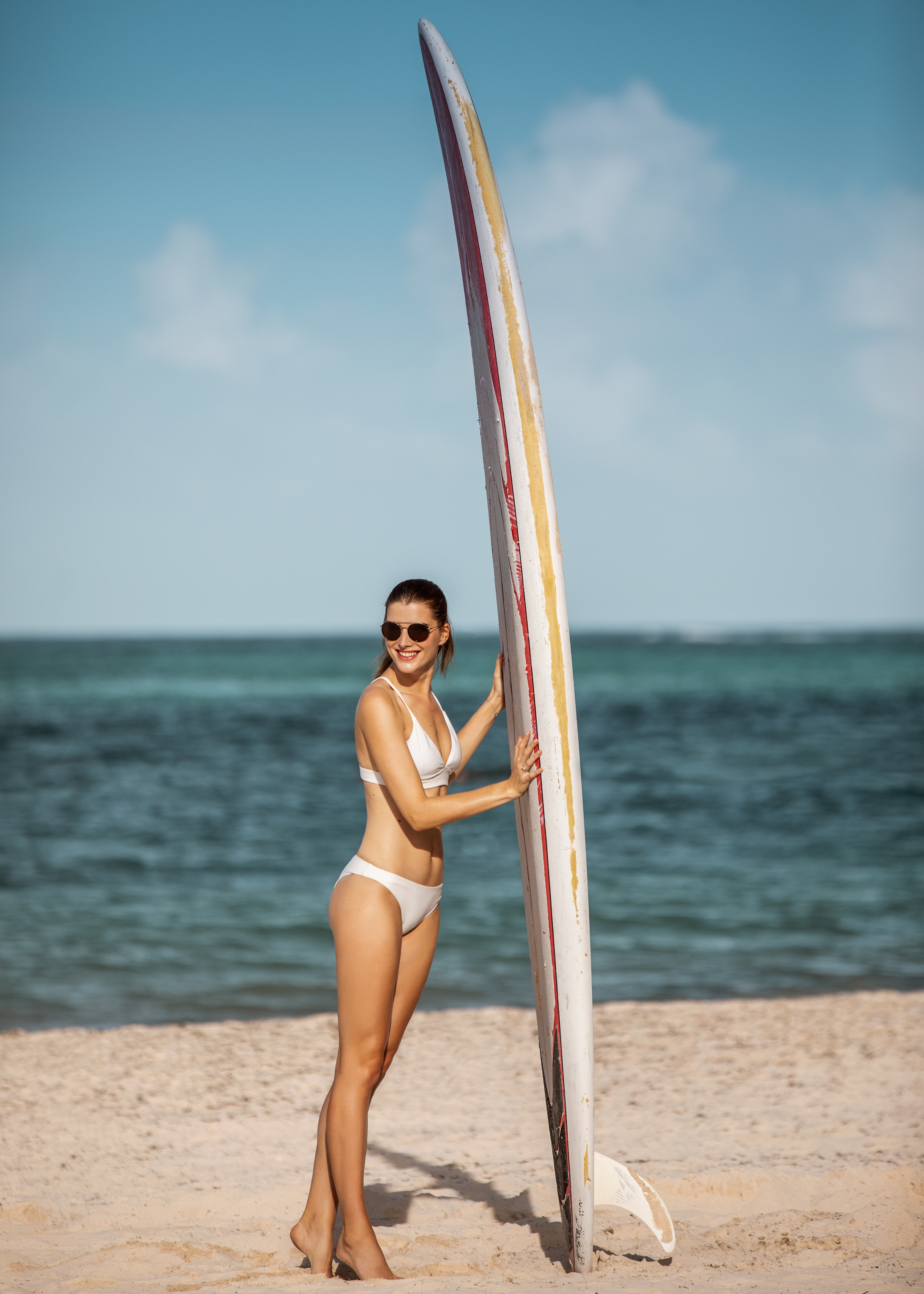 a woman in a garment holding a surfboard on a beach