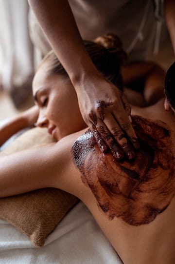 a woman receiving a chocolate scrub on her back