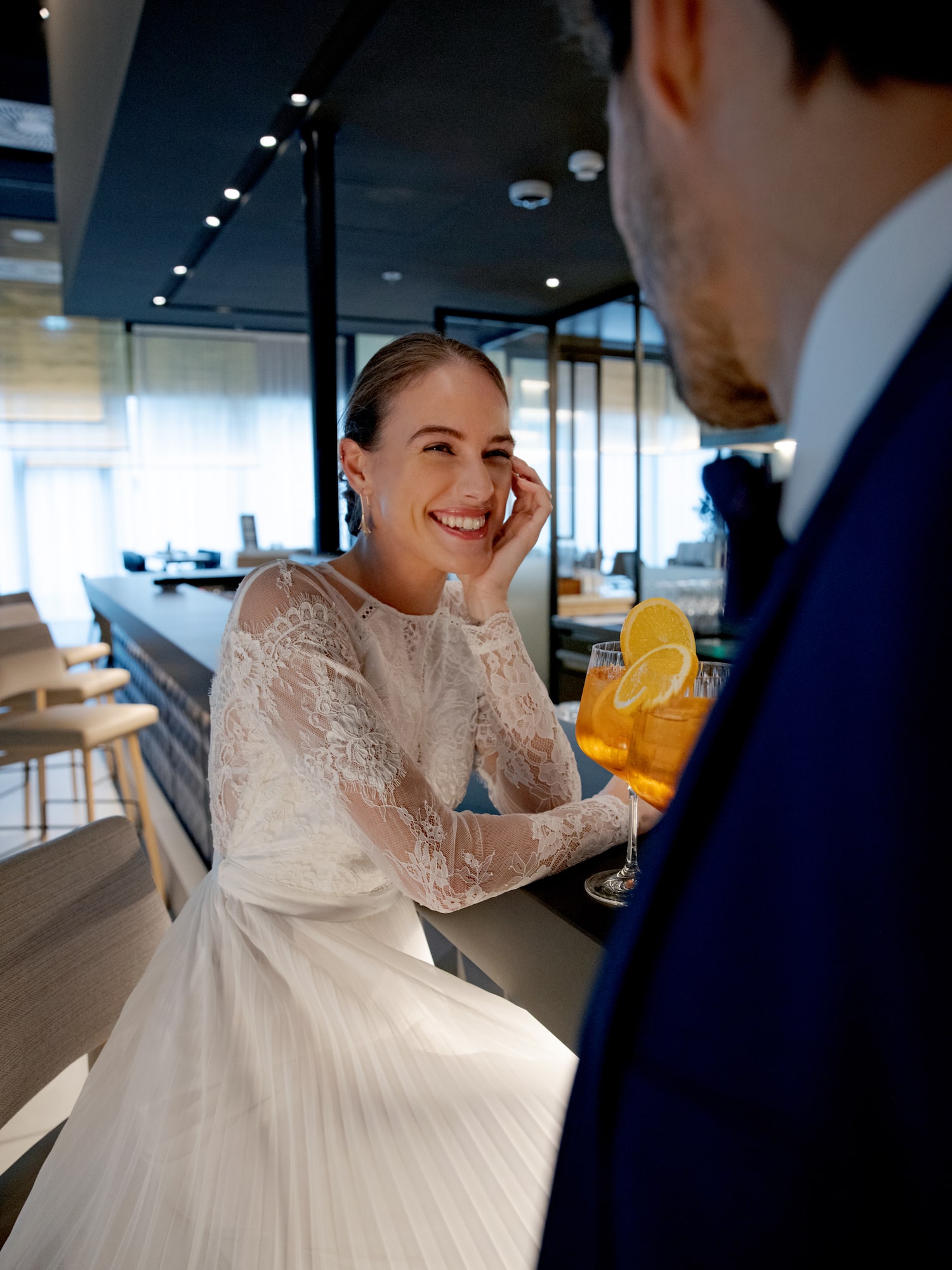 a woman in a white dress sitting at a bar with drinks