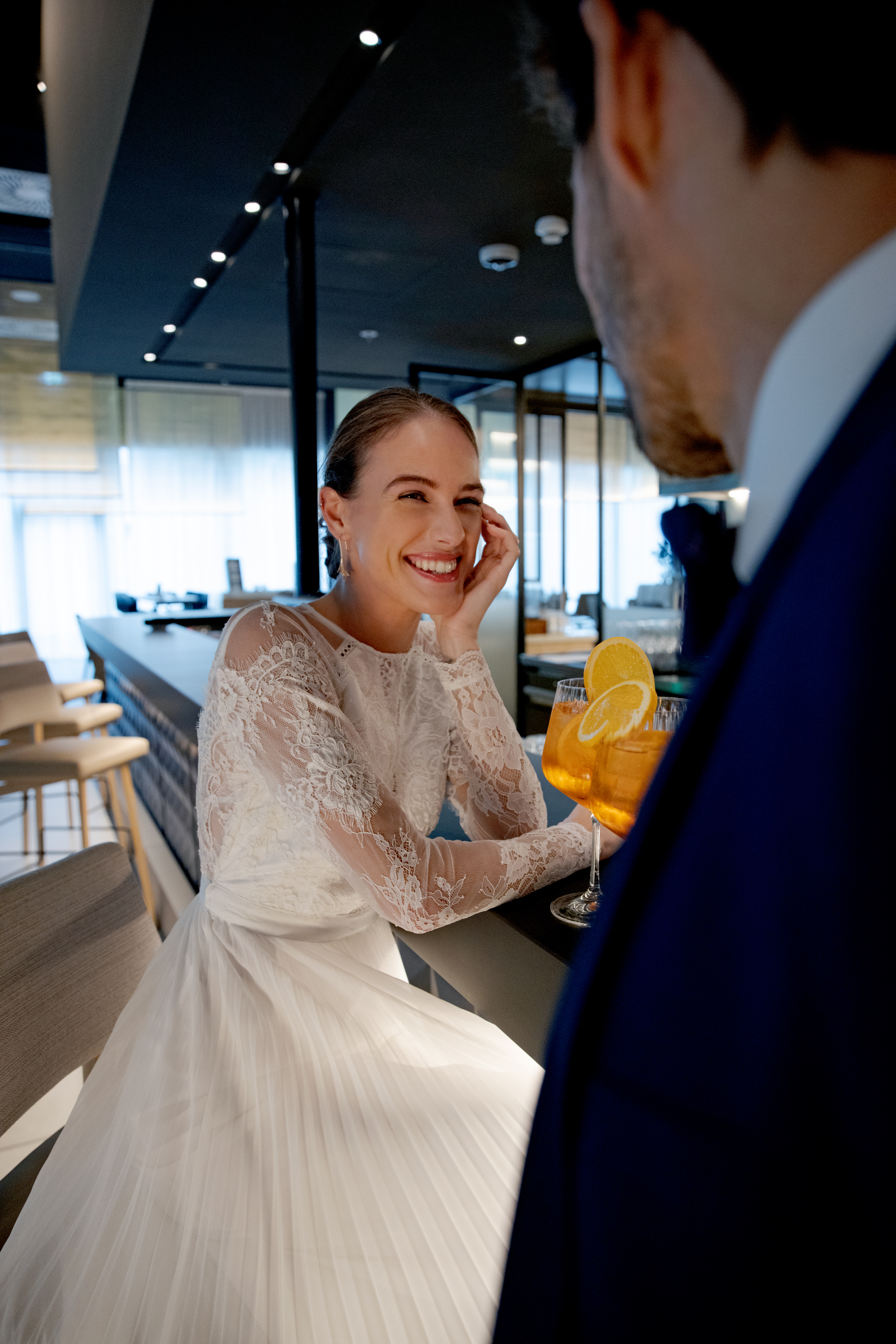 a woman in a white dress sitting at a bar with drinks