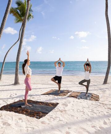 a group of people doing yoga on the beach