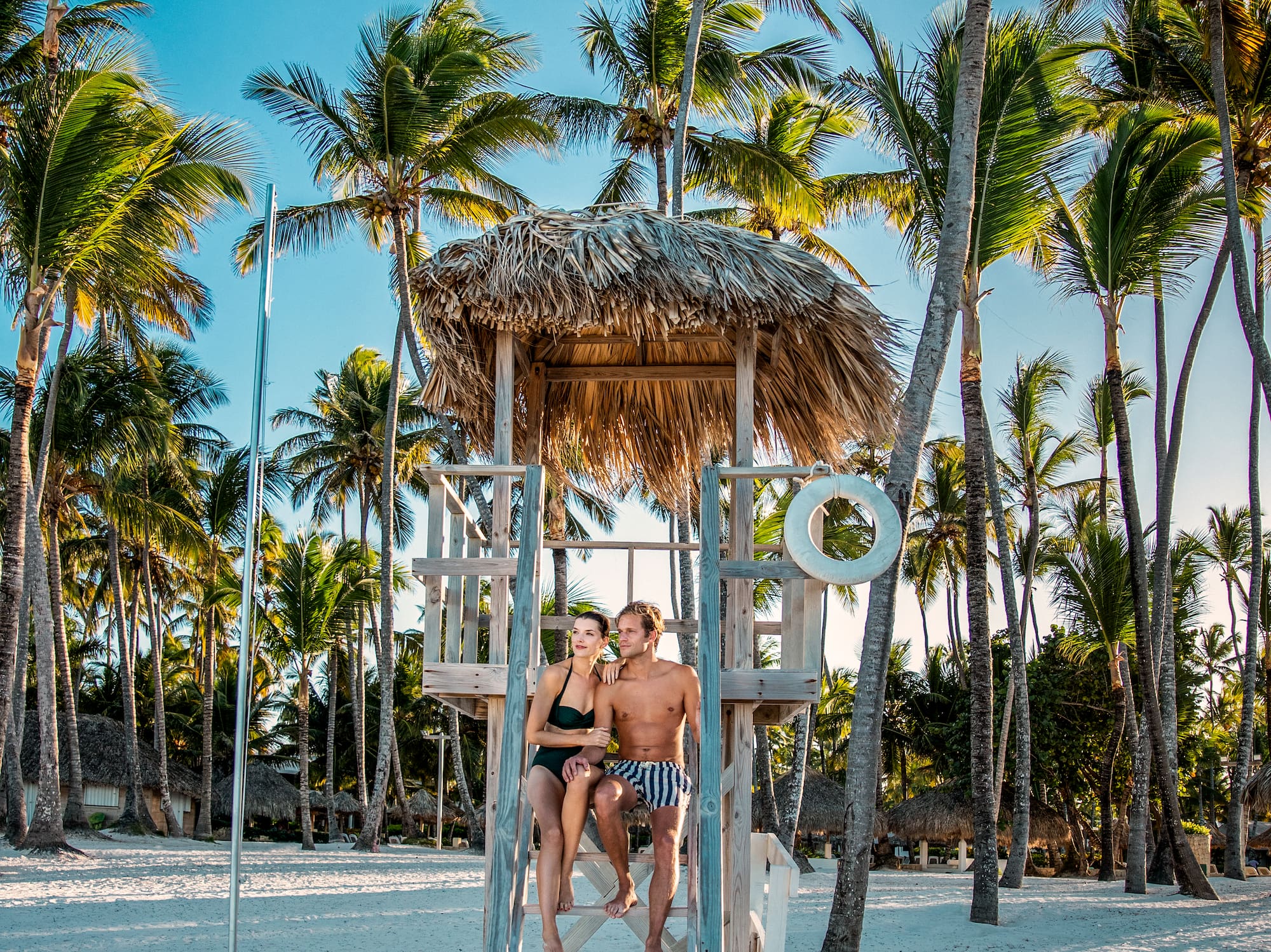 a man and woman sitting on a lifeguard tower on a beach