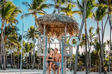 a man and woman sitting on a lifeguard tower on a beach