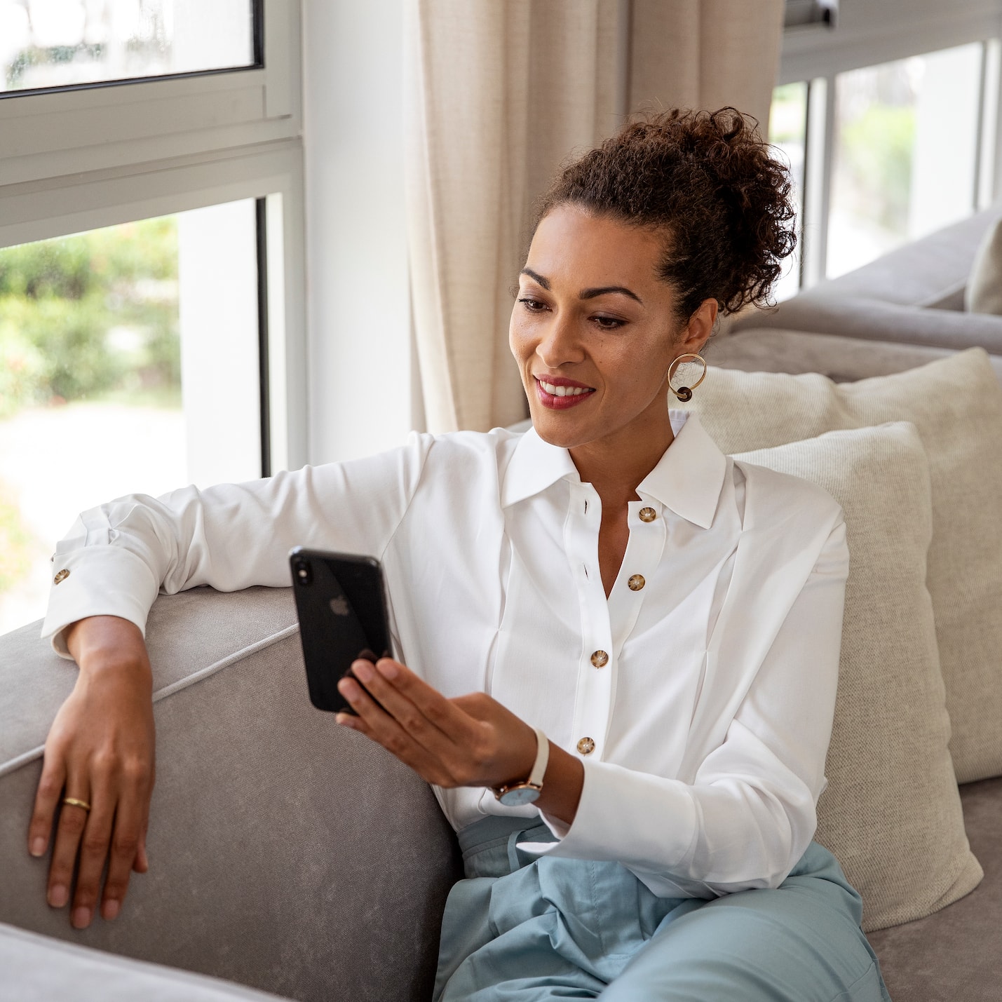 a woman sitting on a couch looking at a phone