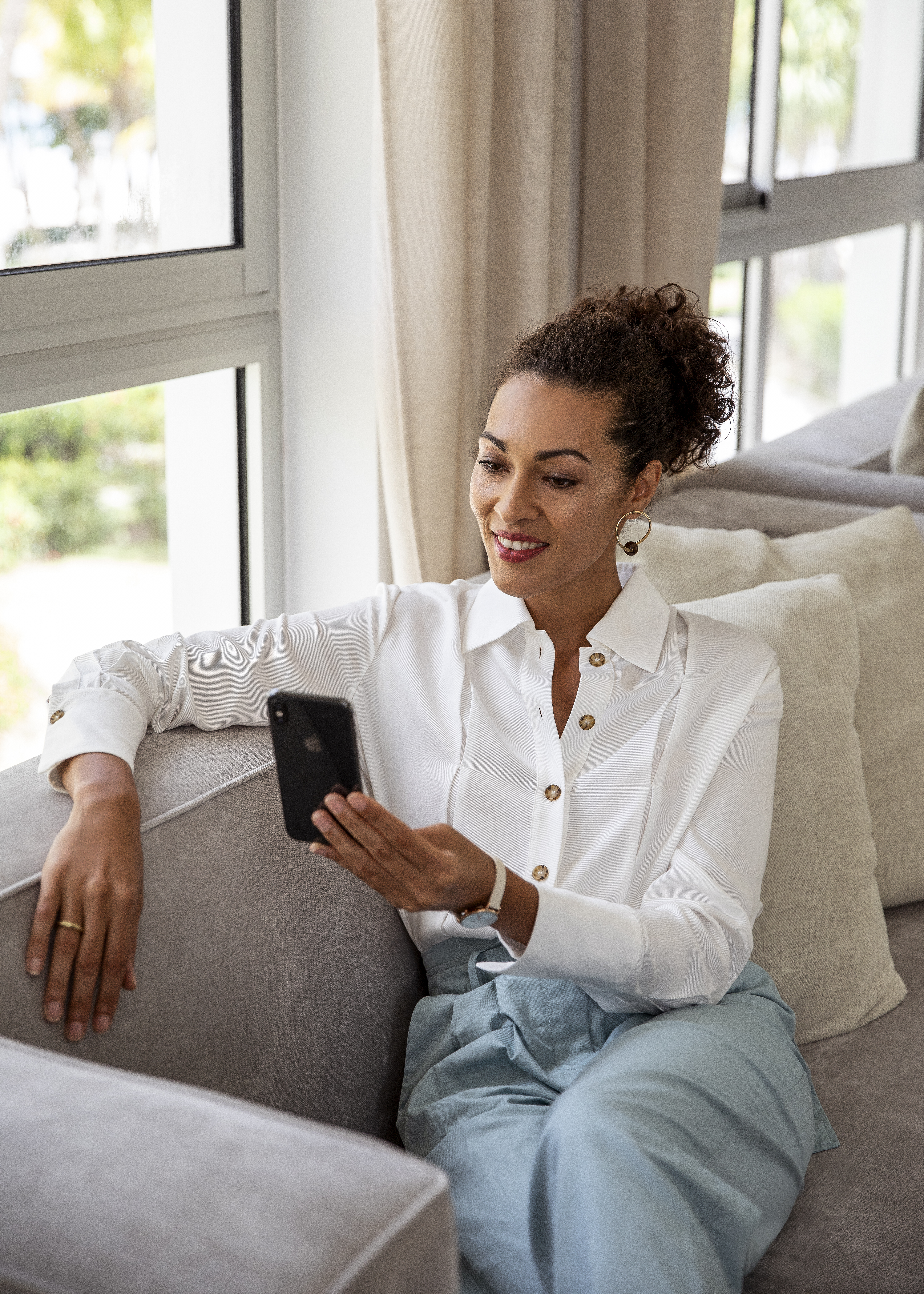 a woman sitting on a couch looking at a phone