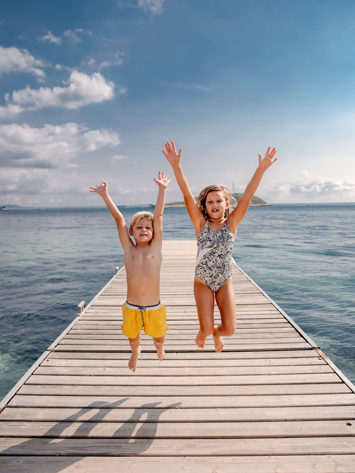 a boy and girl jumping on a dock