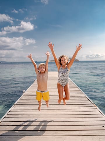 a boy and girl jumping on a dock