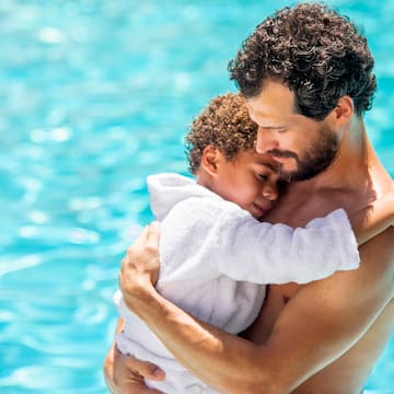 a man holding a child in a pool