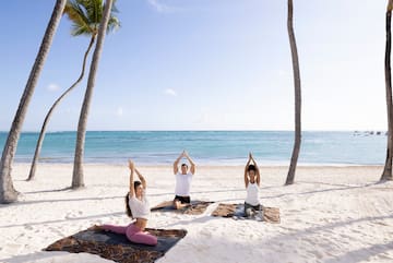 a group of people doing yoga on the beach