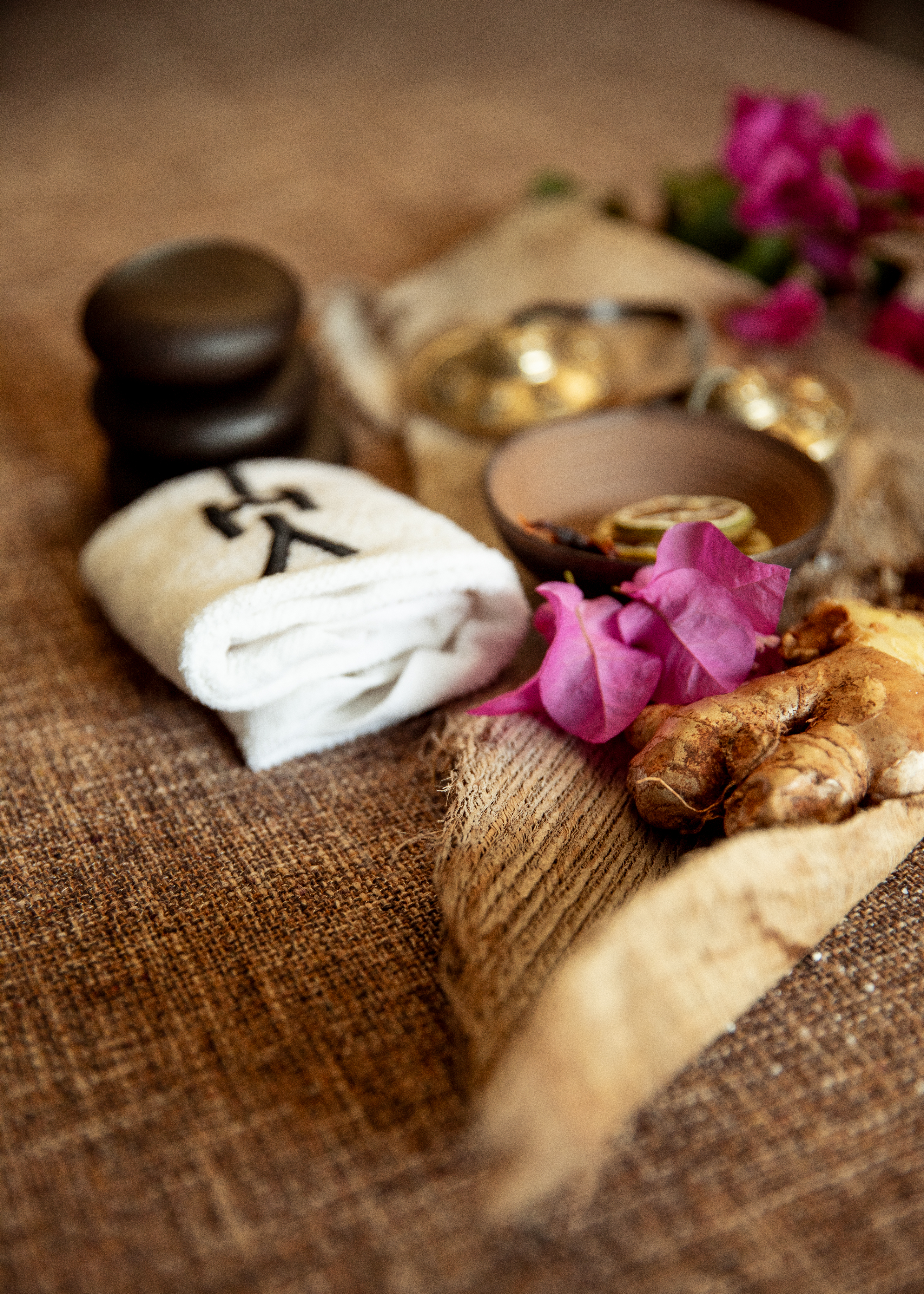 Hot stones, spa towel, ginger, dried citrus, pink flowers for wellness.