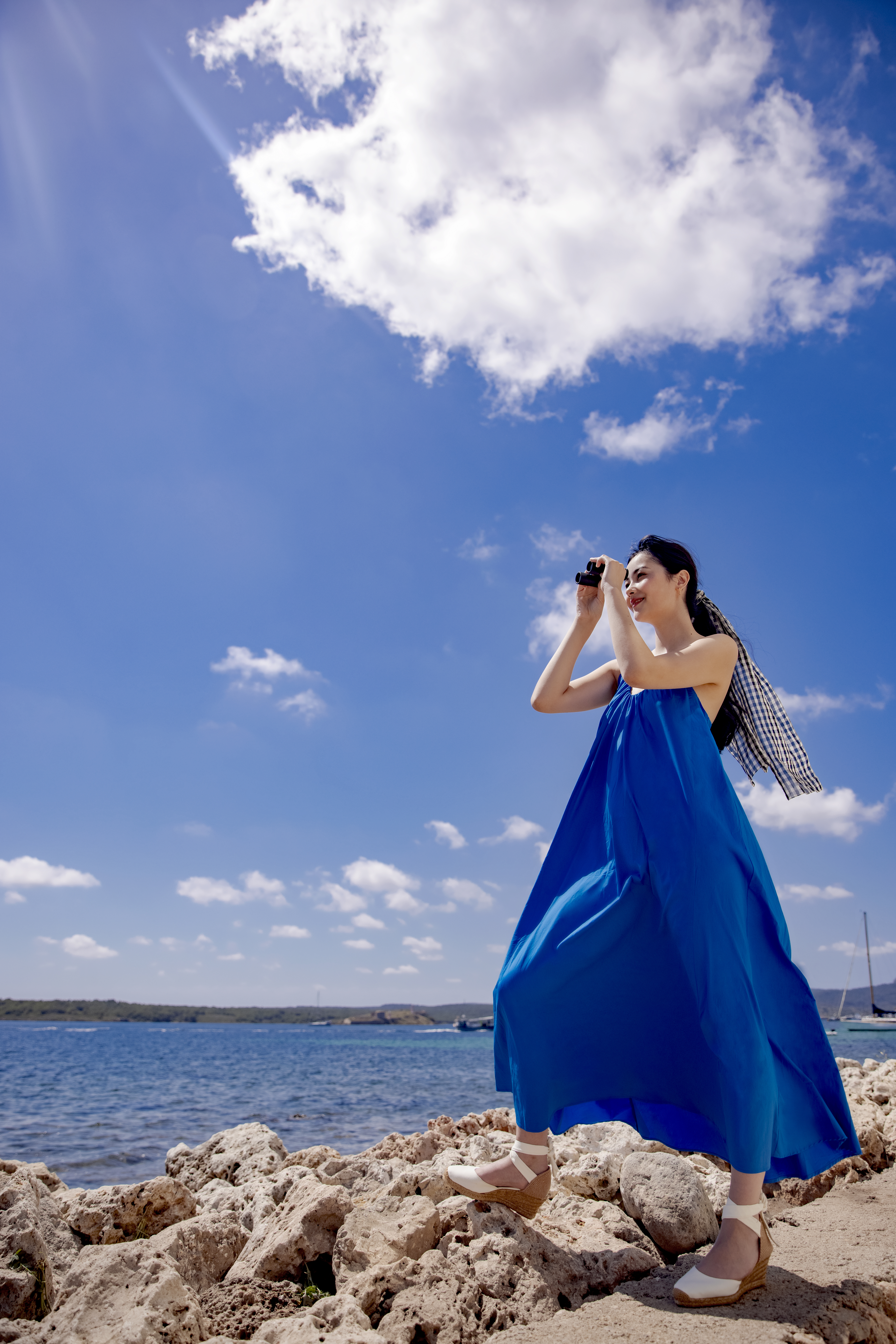 a woman in a blue dress on a beach