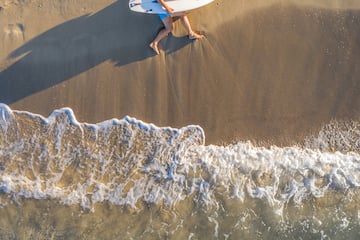 a man lying on the beach with a surfboard