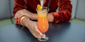 a person holding a glass of orange liquid