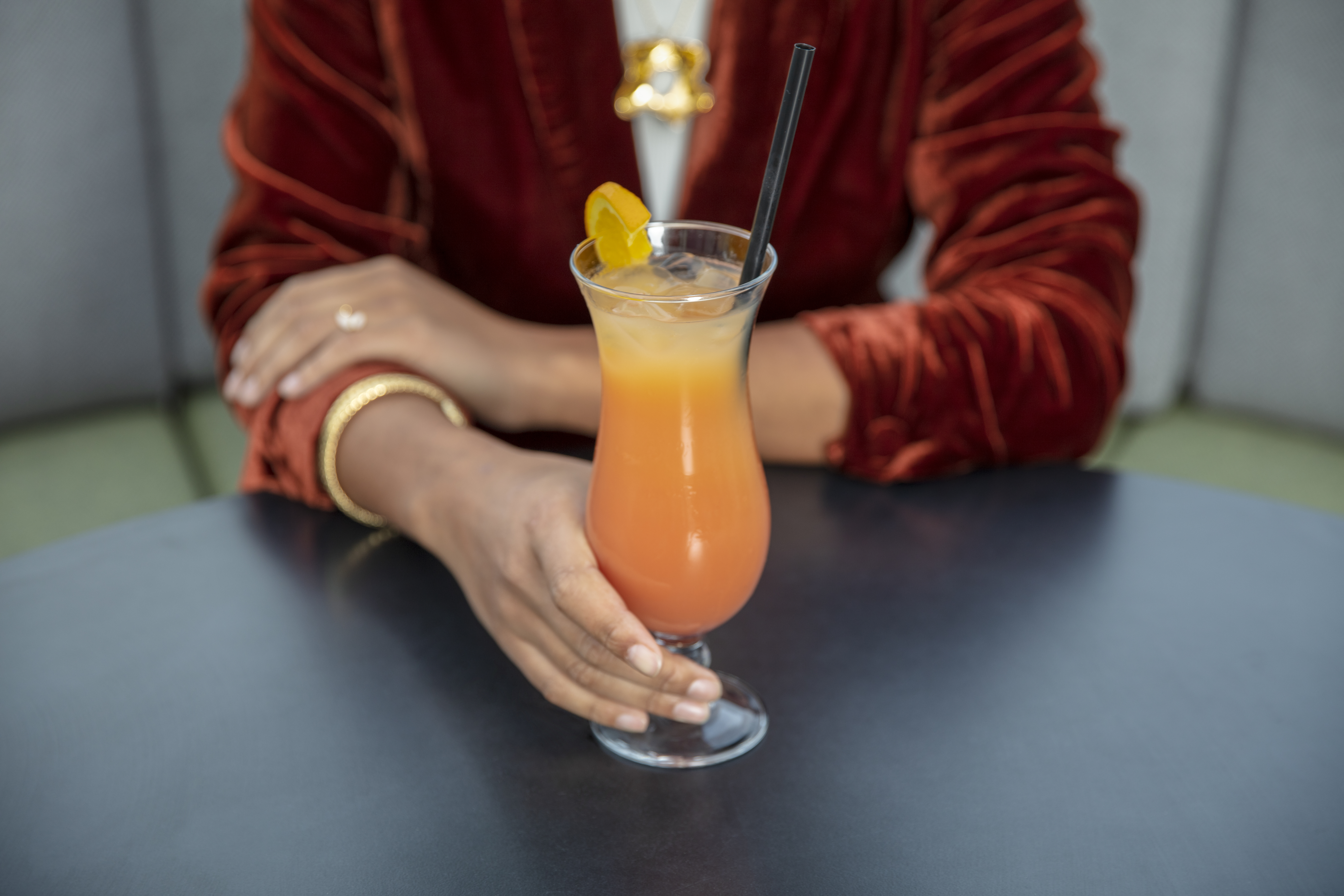 a person holding a glass of orange liquid