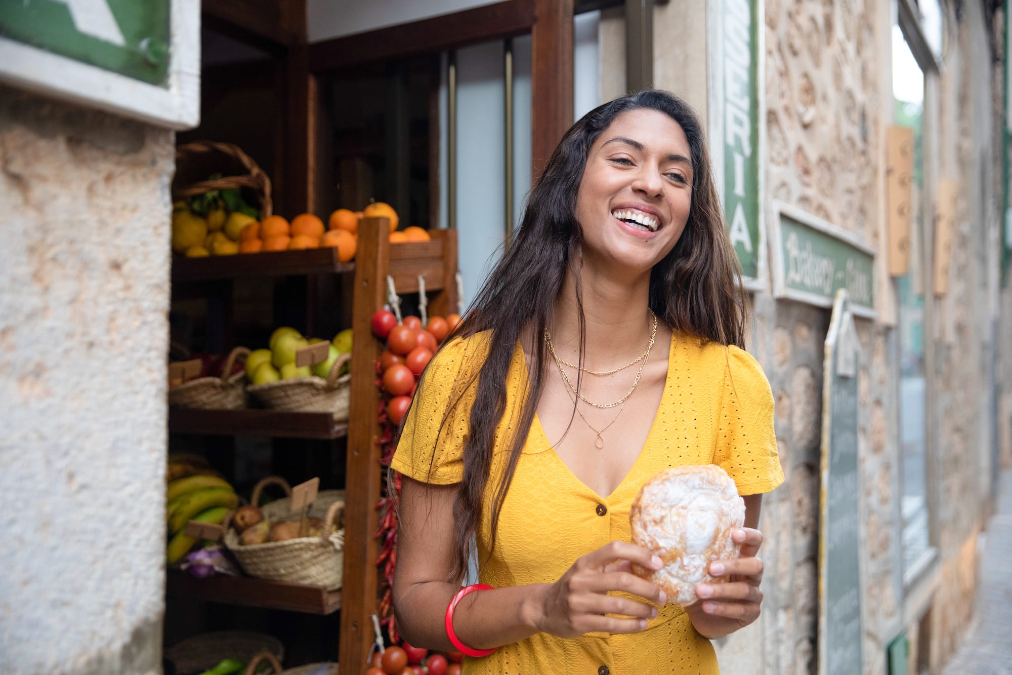 a woman smiling while holding a pastry