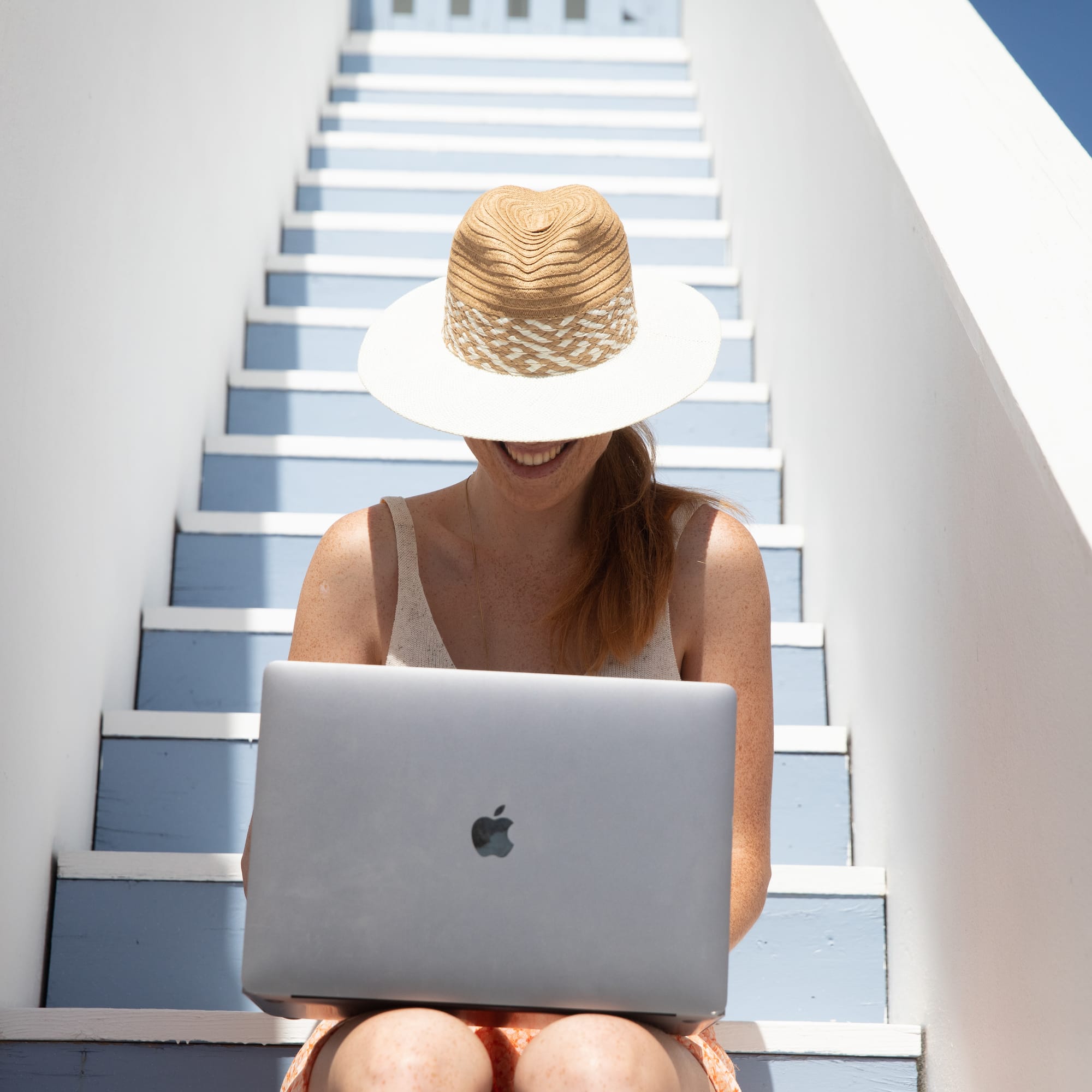 a woman sitting on stairs with a laptop