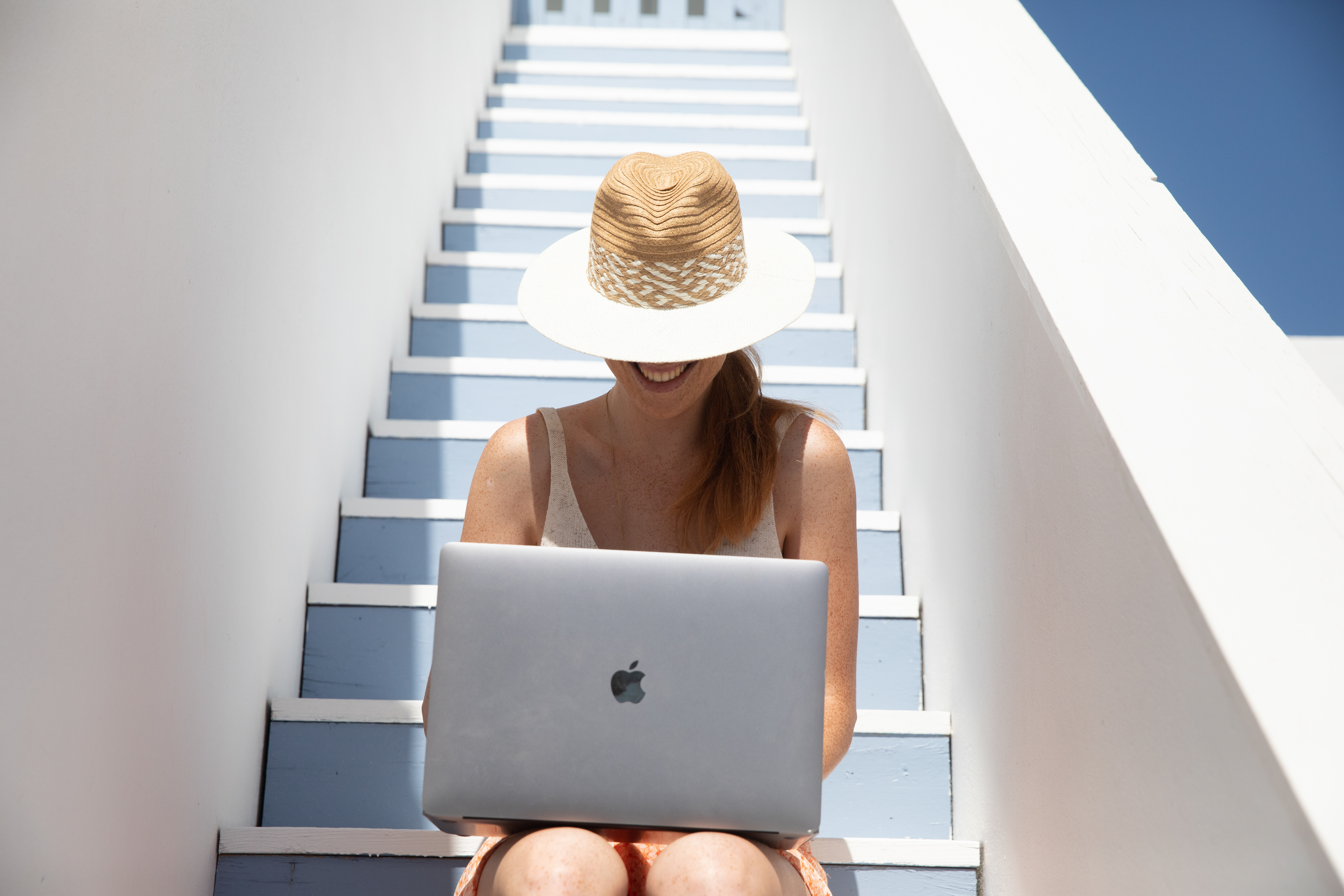 a woman sitting on stairs with a laptop