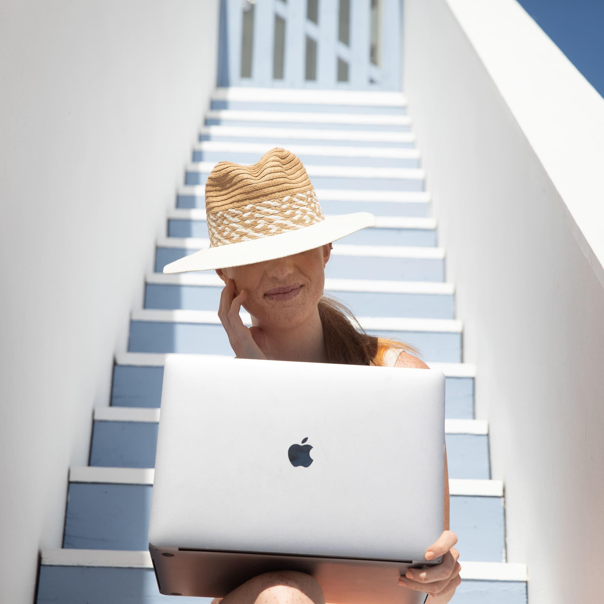 a woman sitting on stairs with a laptop