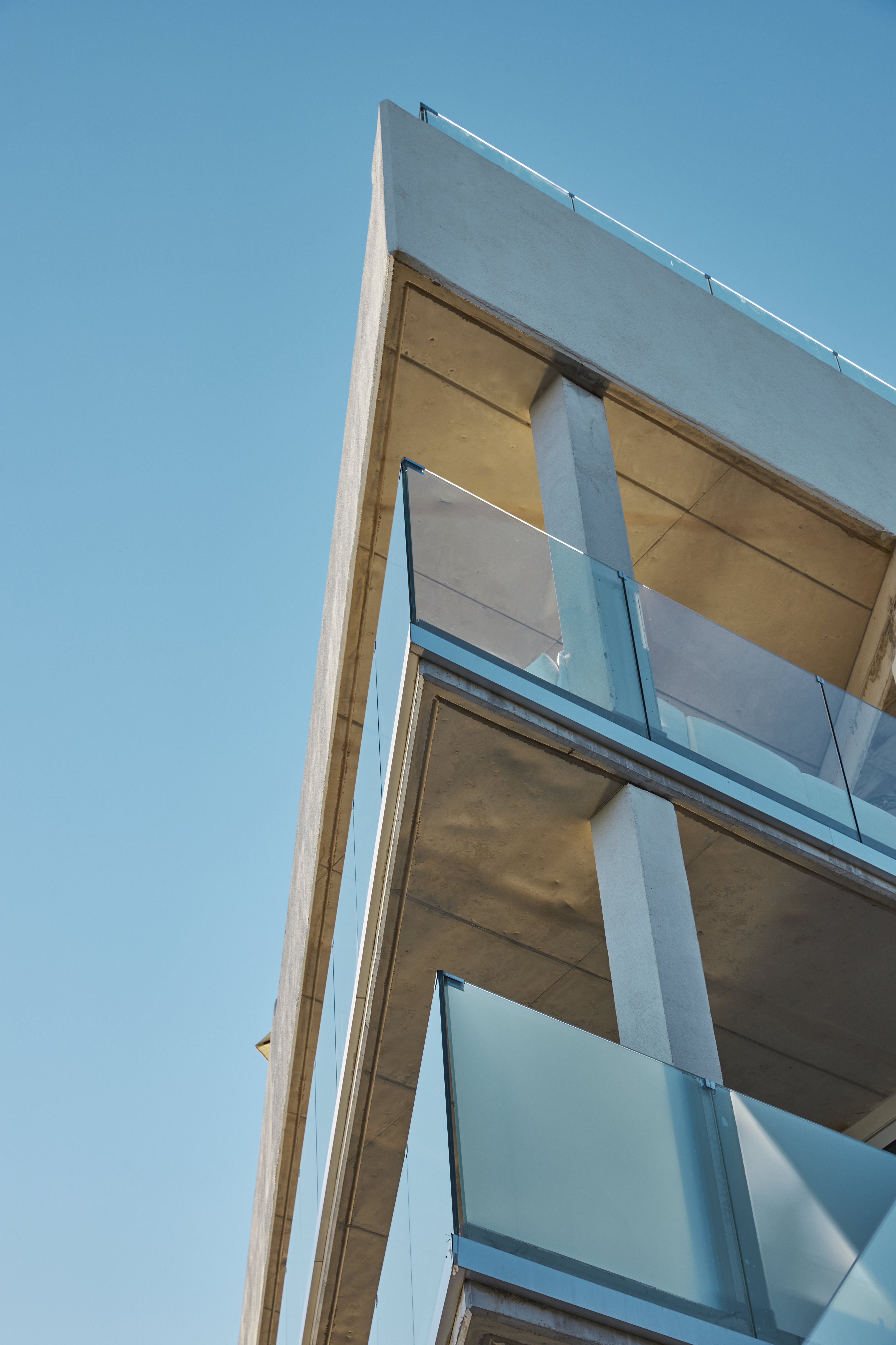 Angular modern concrete building with glass balconies against a blue sky.